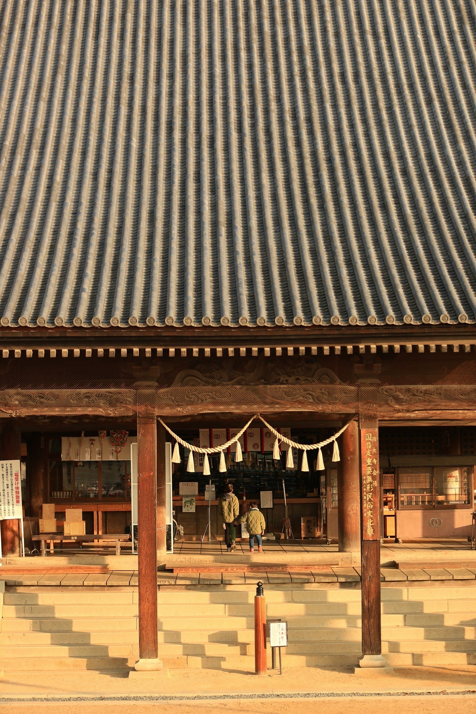 木の軒下に下がる提灯とお守りのある神社の参拝スペース