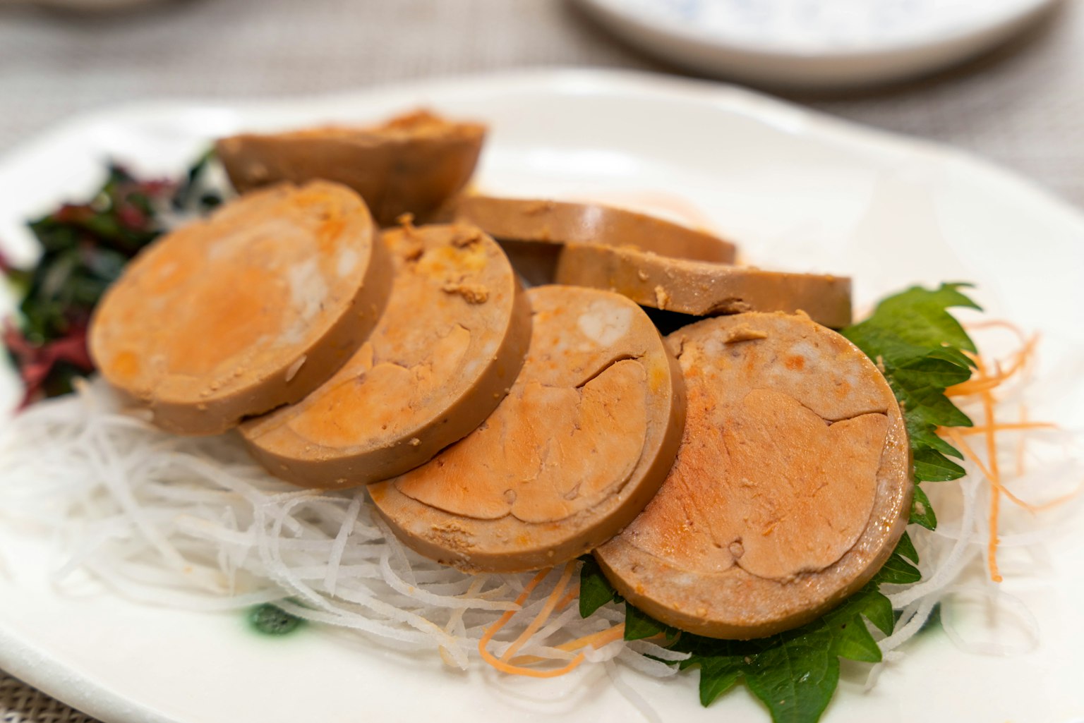 切片的素食香肠摆放在盘子里，配有细白面条和绿色叶子