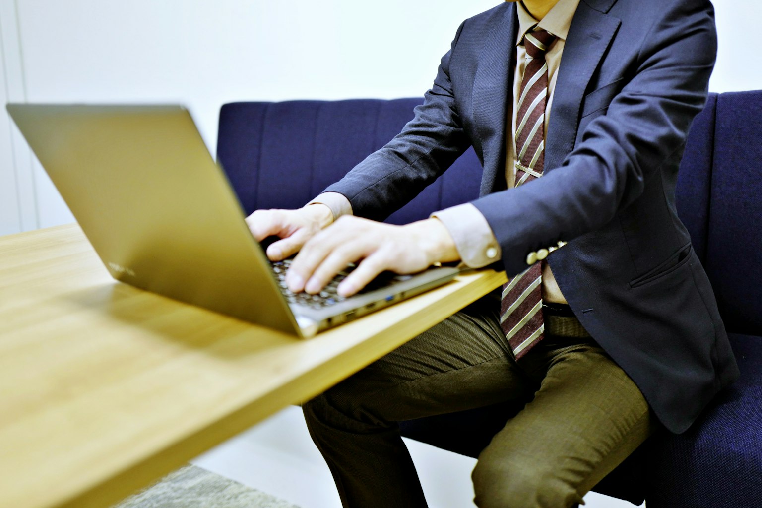 Ein Mann in Anzug, der an einem Tisch einen Laptop benutzt