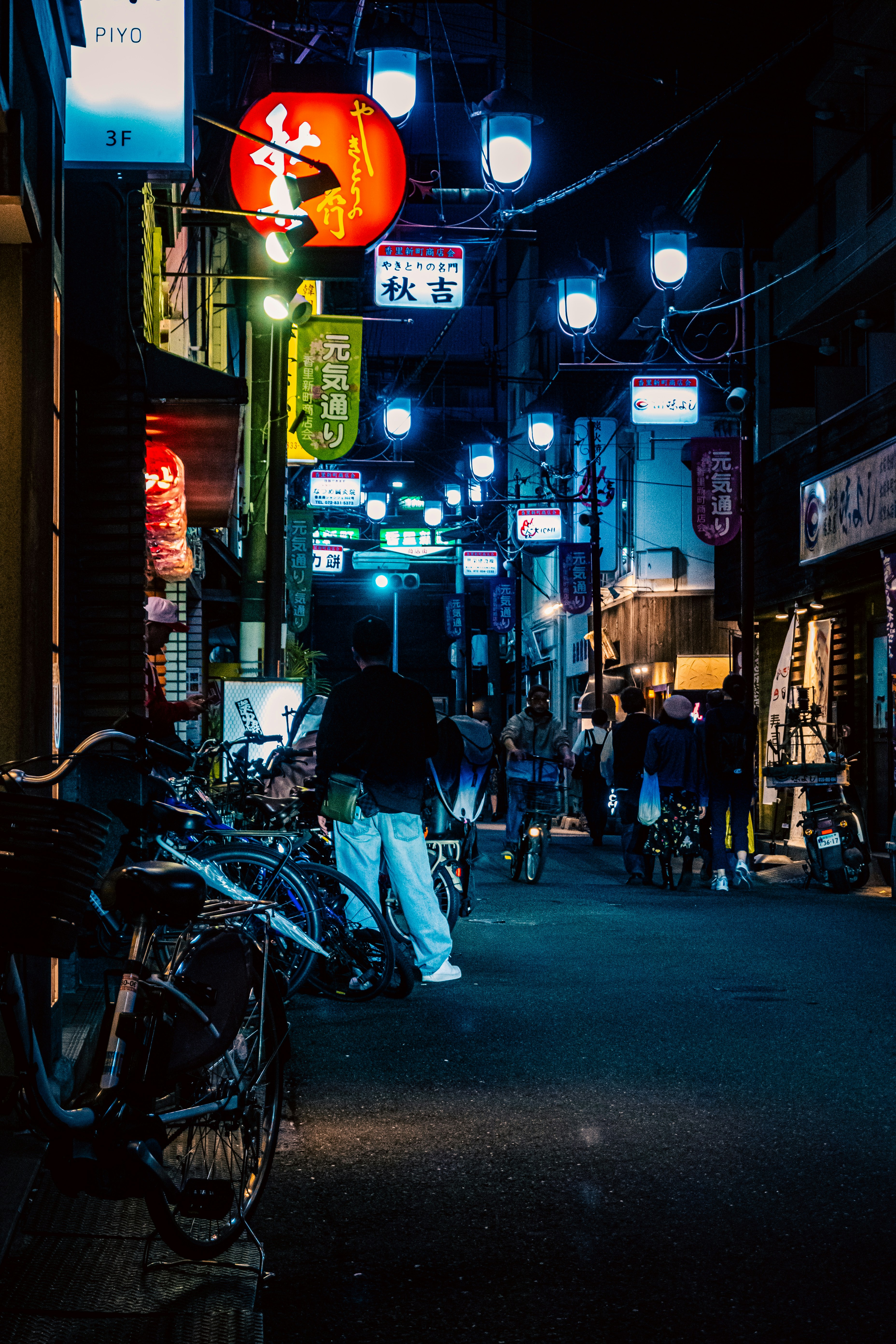 ネオンが灯る路地に並ぶ自転車と看板のある夜の商店街
