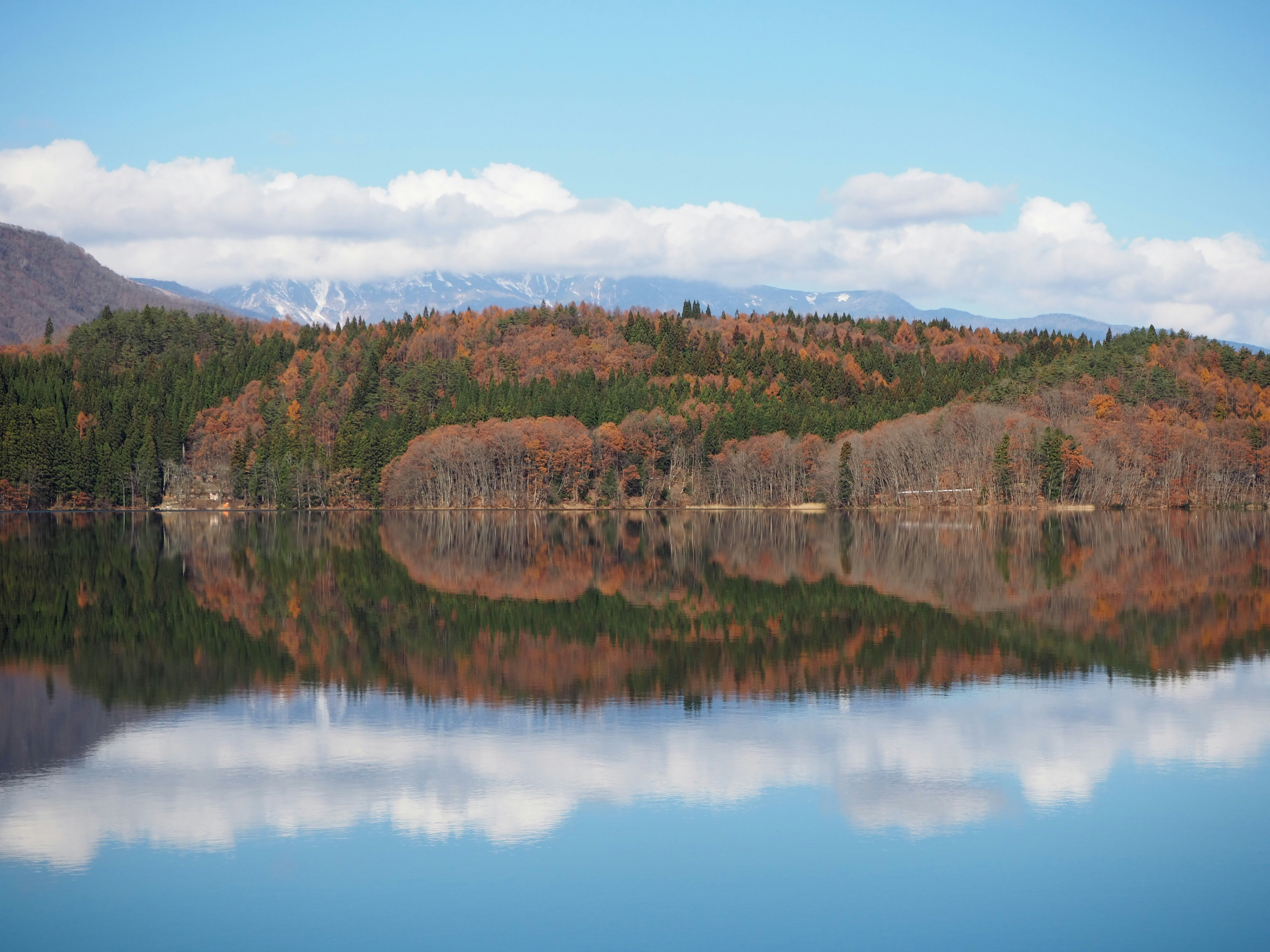 Un lago tranquilo que refleja montañas de otoño y follaje