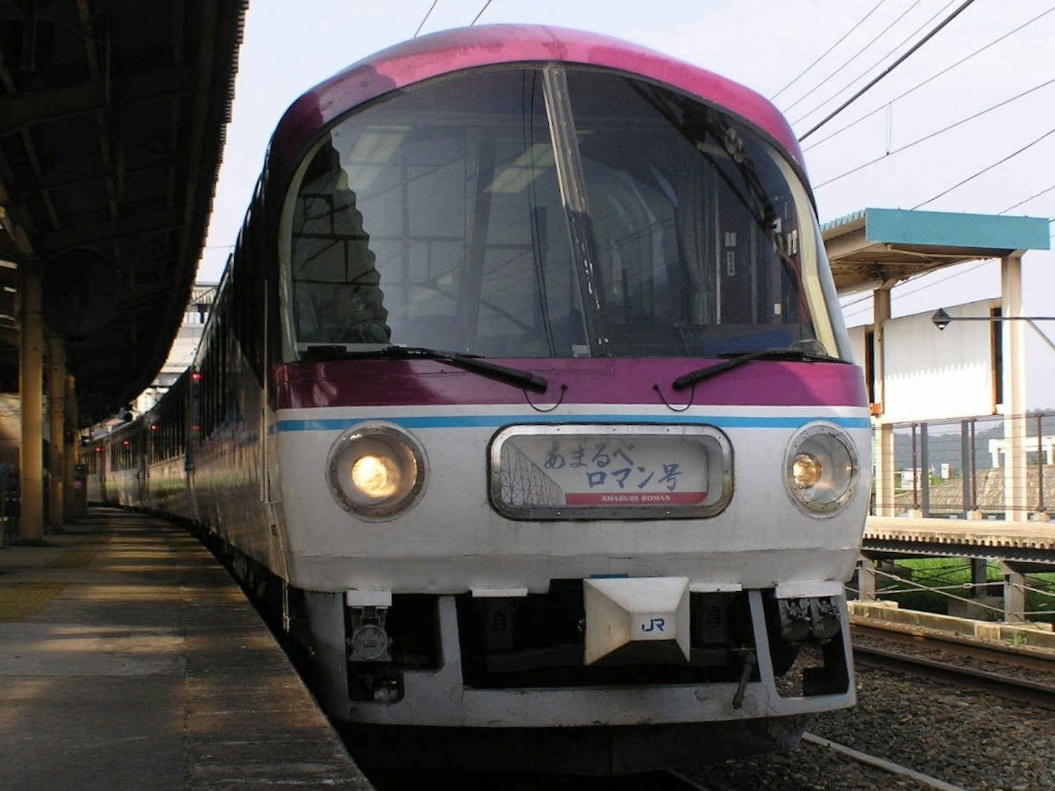 Kereta modern dengan atap merah muda berhenti di stasiun