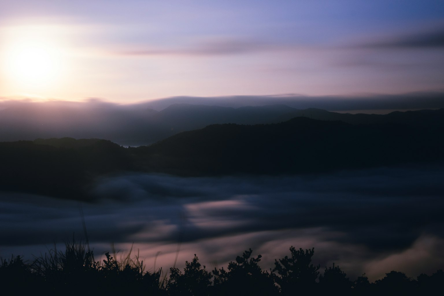 Paesaggio montano avvolto nella nebbia con il sole che sorge