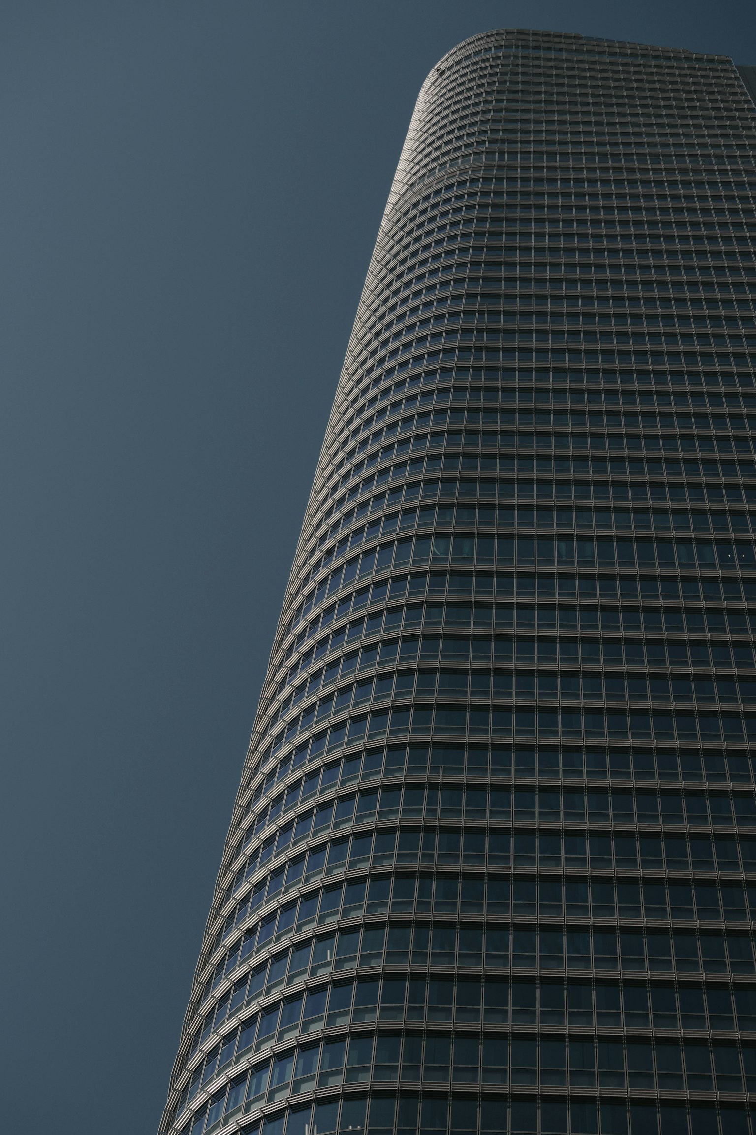 Image of a modern skyscraper viewed from below highlighting its curved glass facade