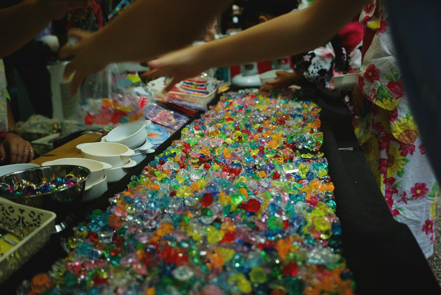 ขนมสีสันสดใสเหมือนเจลลี่กระจายอยู่บนโต๊ะที่มีมือยื่นไปหา