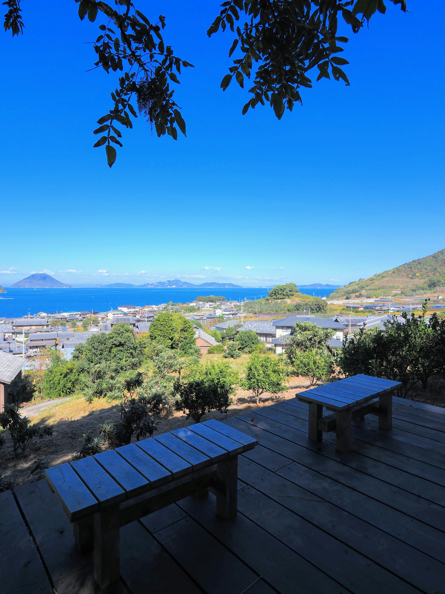 Tables et chaises en bois surplombant un beau paysage avec ciel bleu et mer