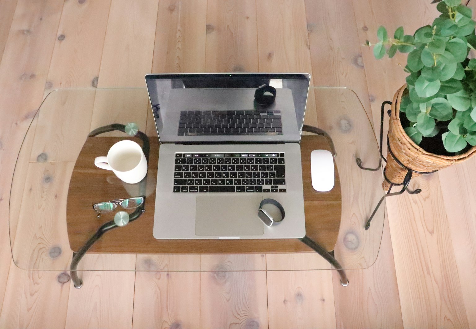 Laptop e mouse su un tavolo di legno con una tazza di caffè e una pianta in vaso