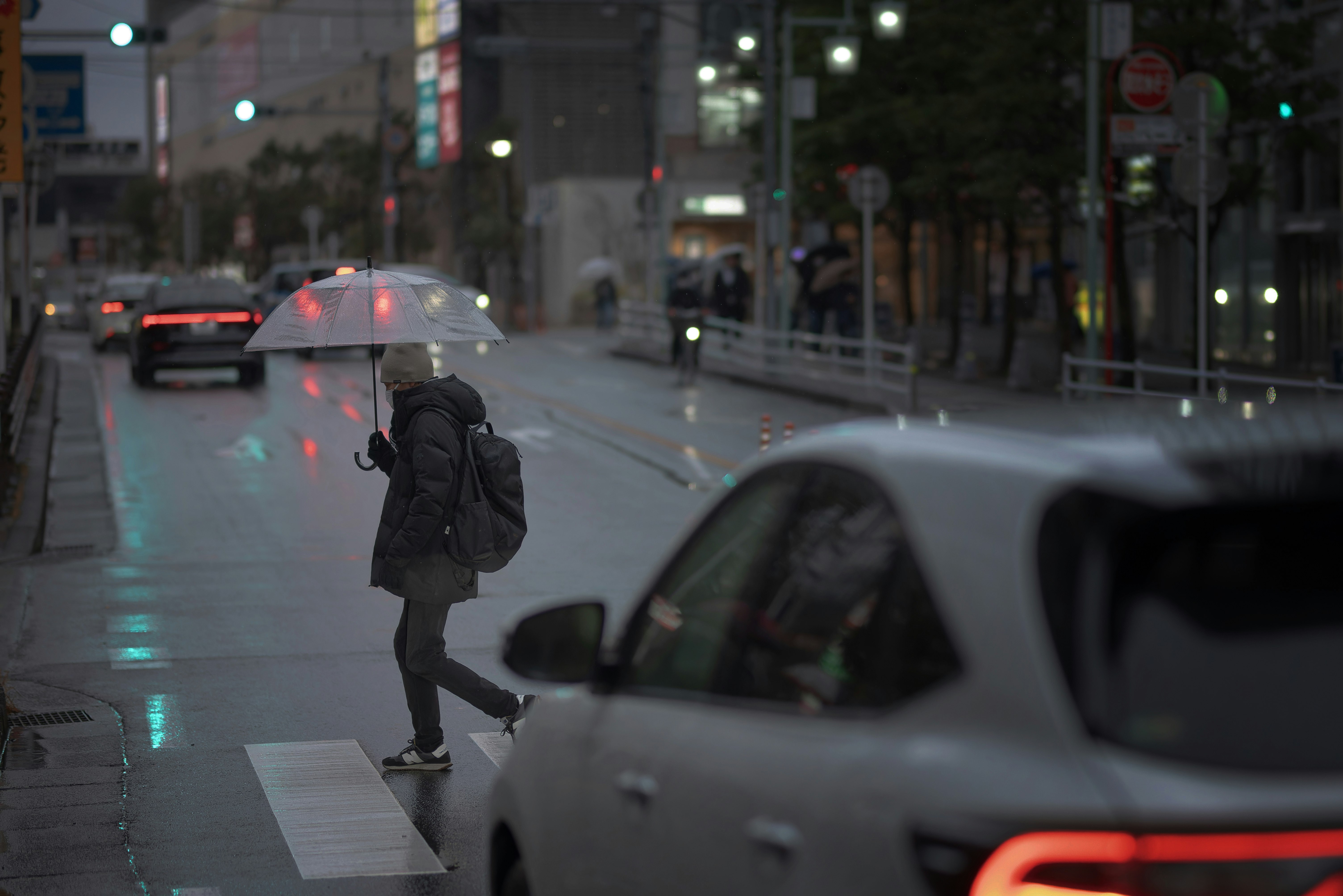 雨の街で傘をさす人と車のある交差点