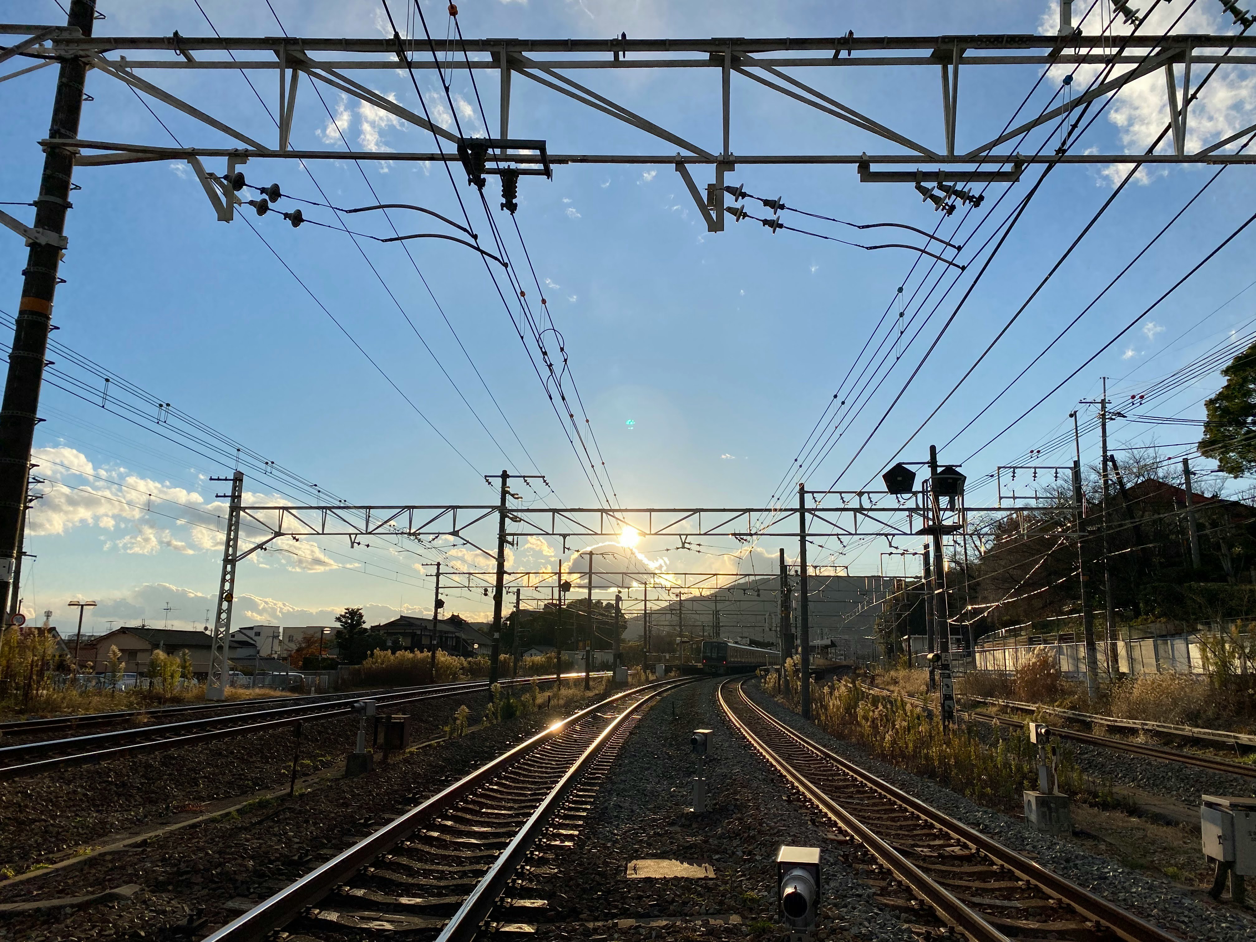 Railroad tracks and overhead catenary at a level crossing in sunset light