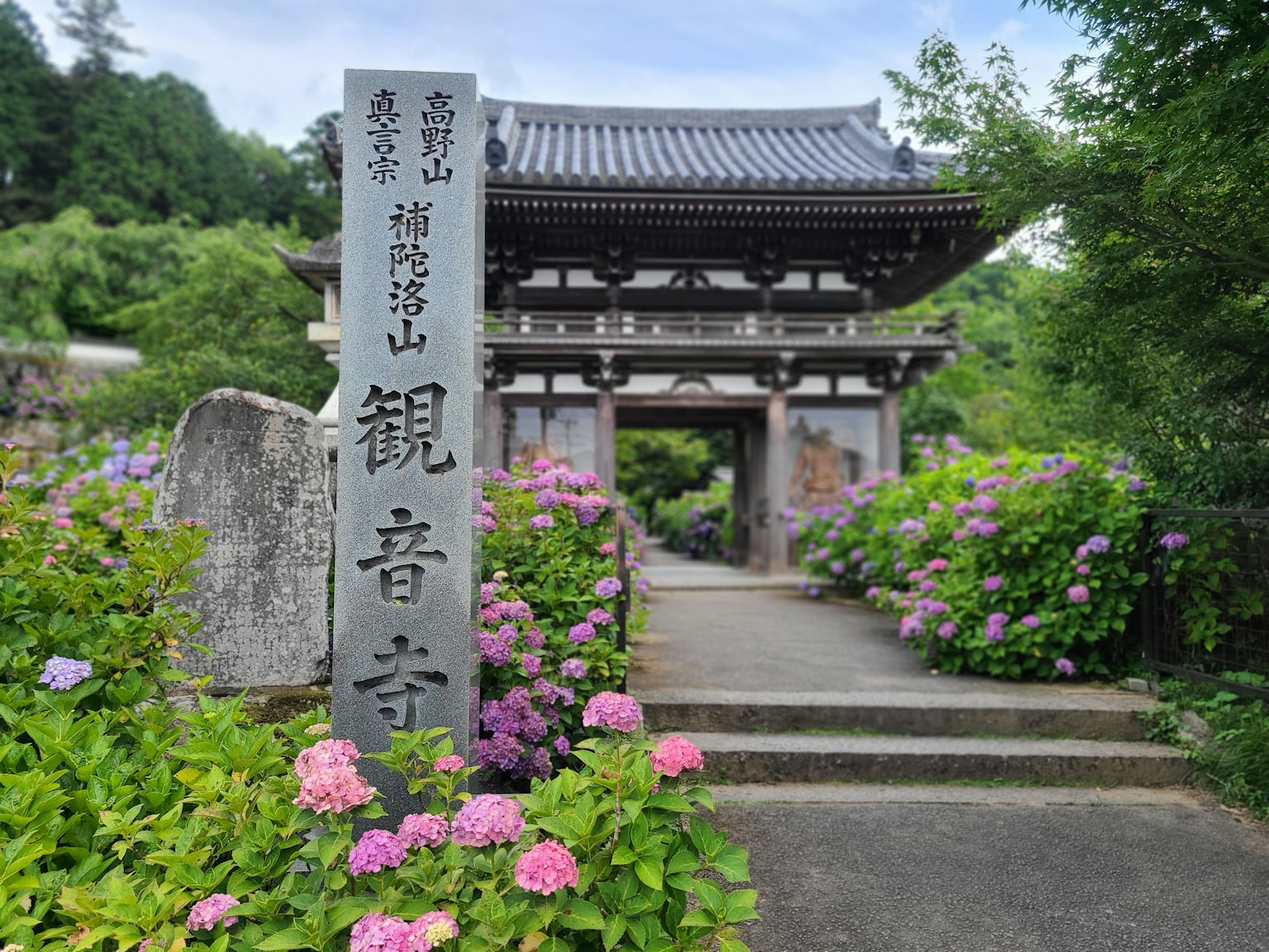 Pintu masuk Kannonji Temple dengan monumen batu dan bunga berwarna-warni