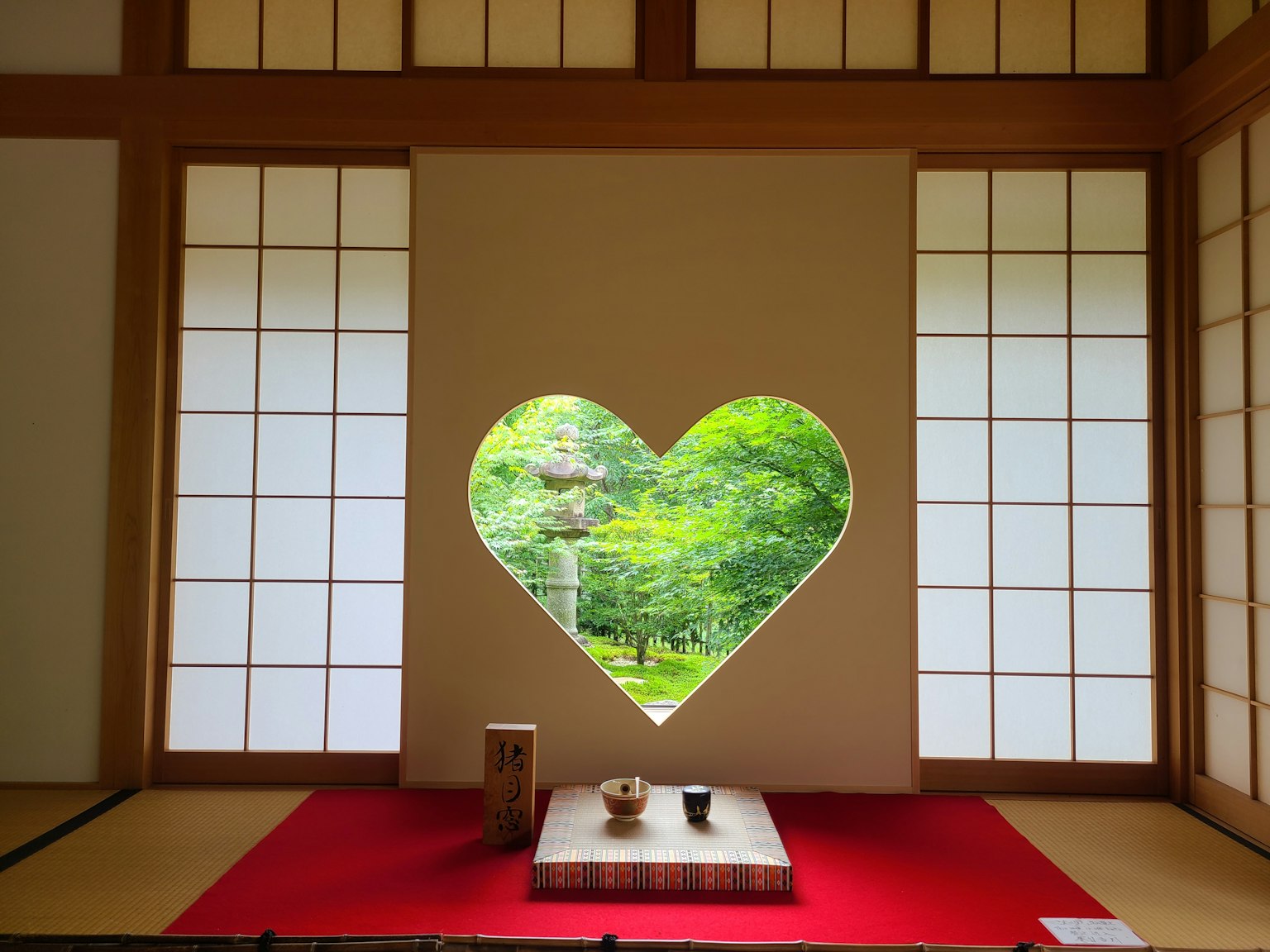 Intérieur d'une pièce japonaise avec une fenêtre en forme de cœur révélant un paysage verdoyant