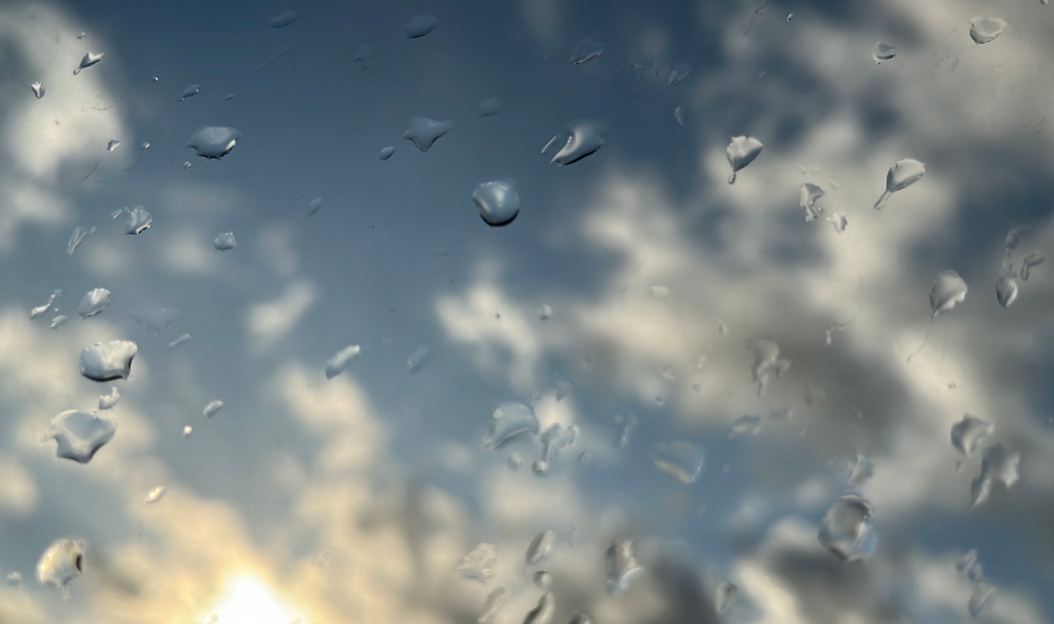 Raindrops on a window with clouds and sky