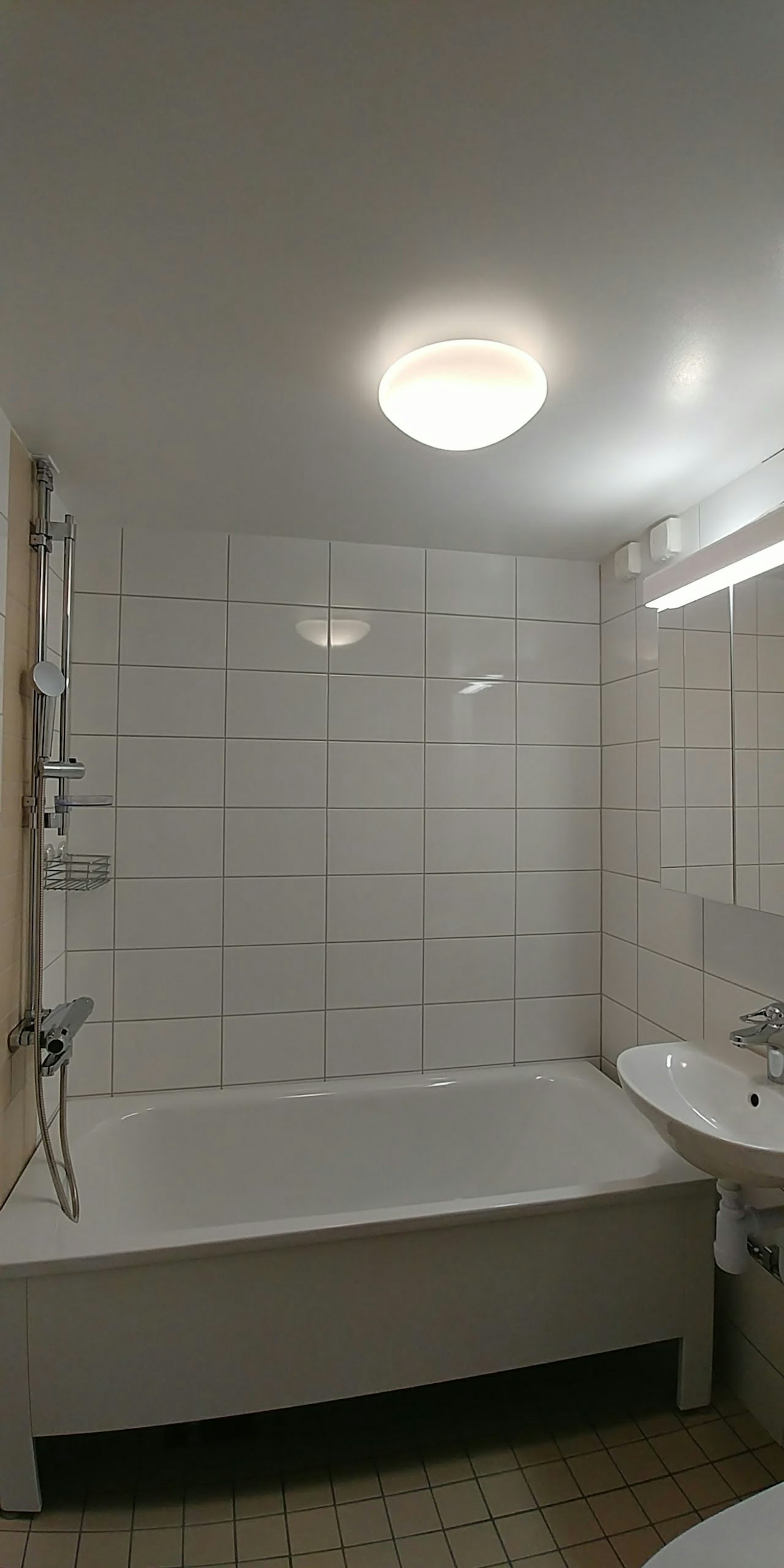 Sauberes, hell erleuchtetes Badezimmer mit Badewanne und Waschbecken