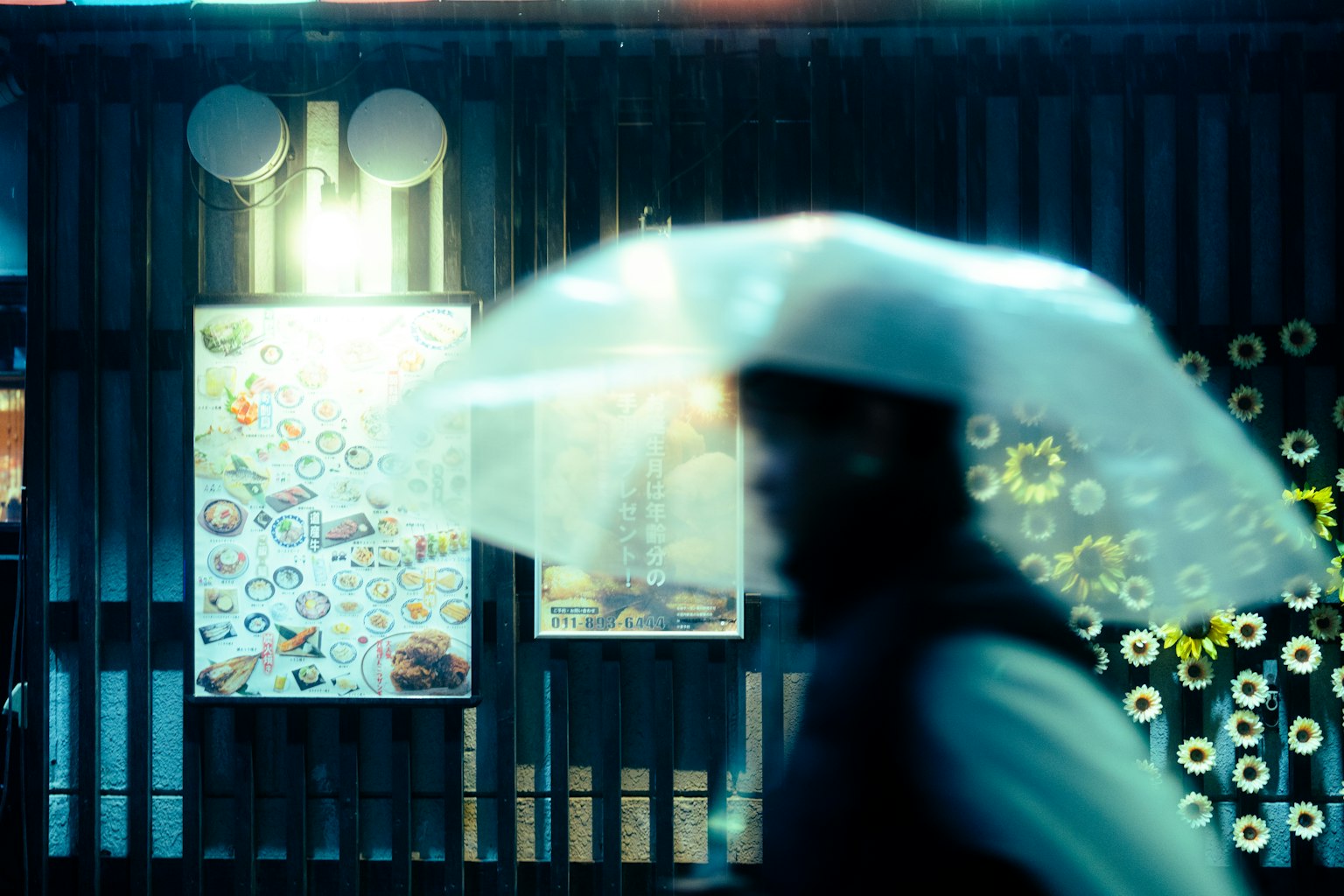 Personne marchant avec un parapluie transparent sous la pluie avec des affiches colorées en arrière-plan