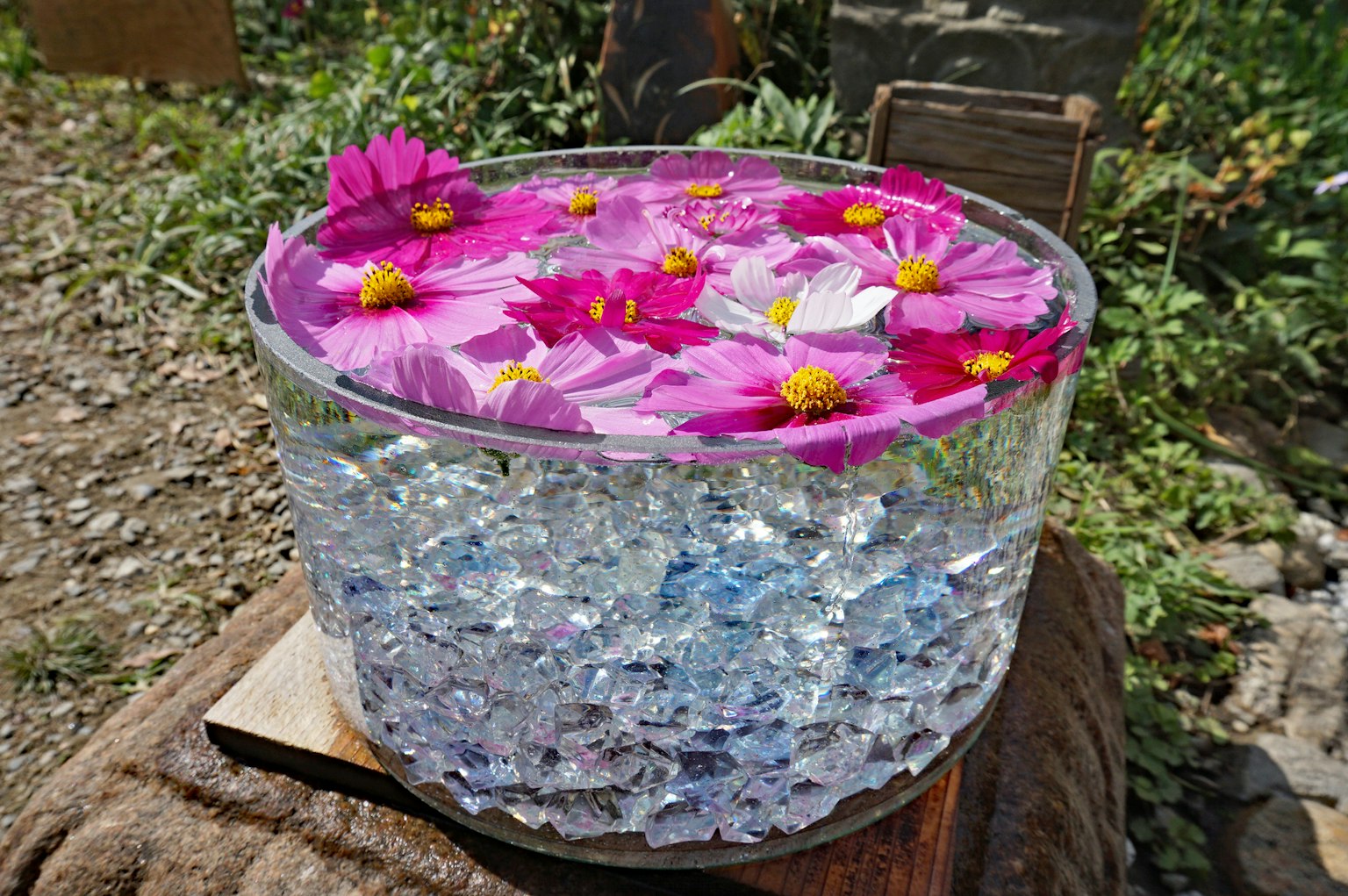 透明容器内装满蓝色水晶和漂浮的粉色花朵