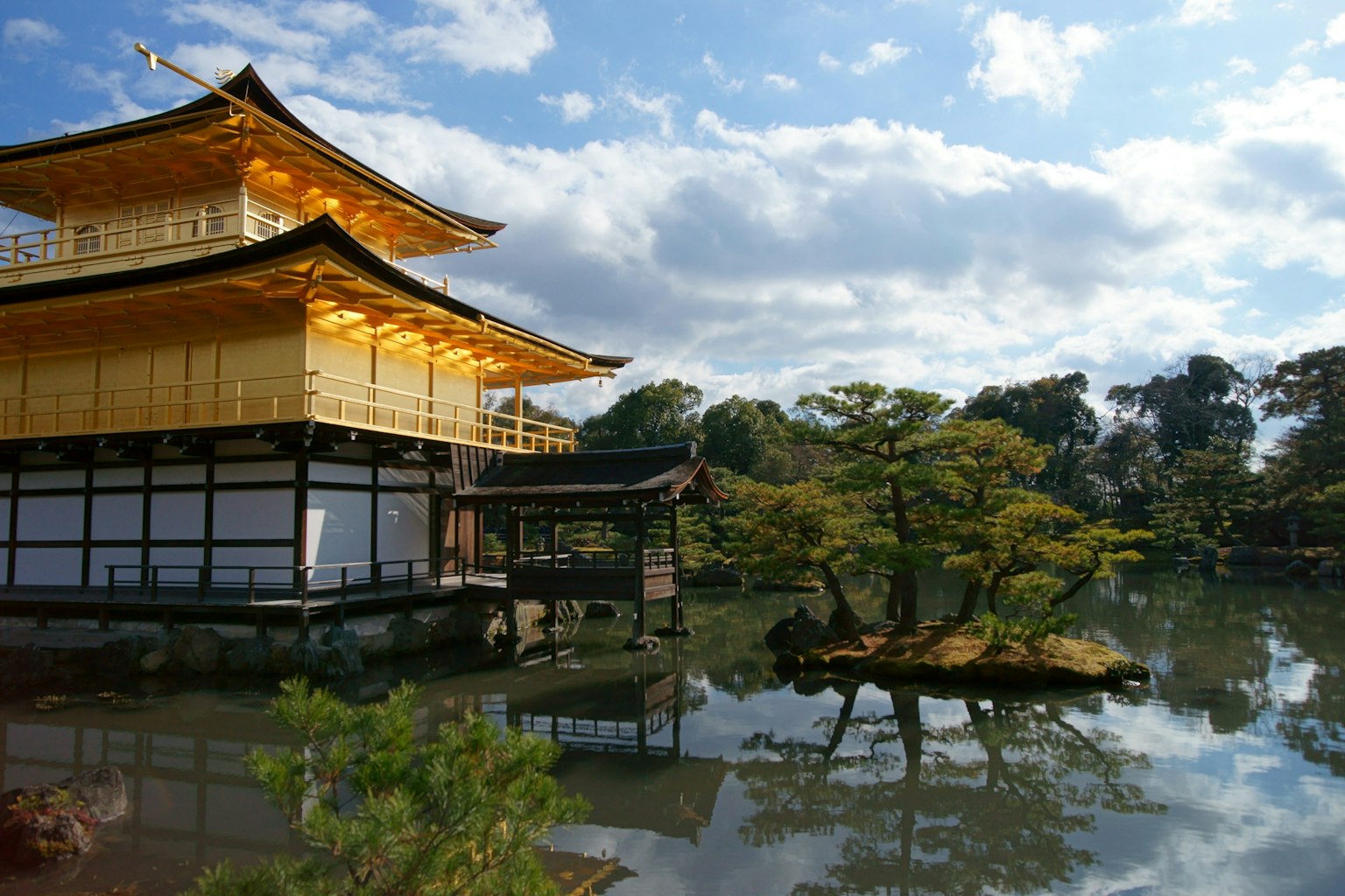 Vue magnifique du Kinkaku-ji se reflétant dans l'eau avec une structure dorée et des arbres verts