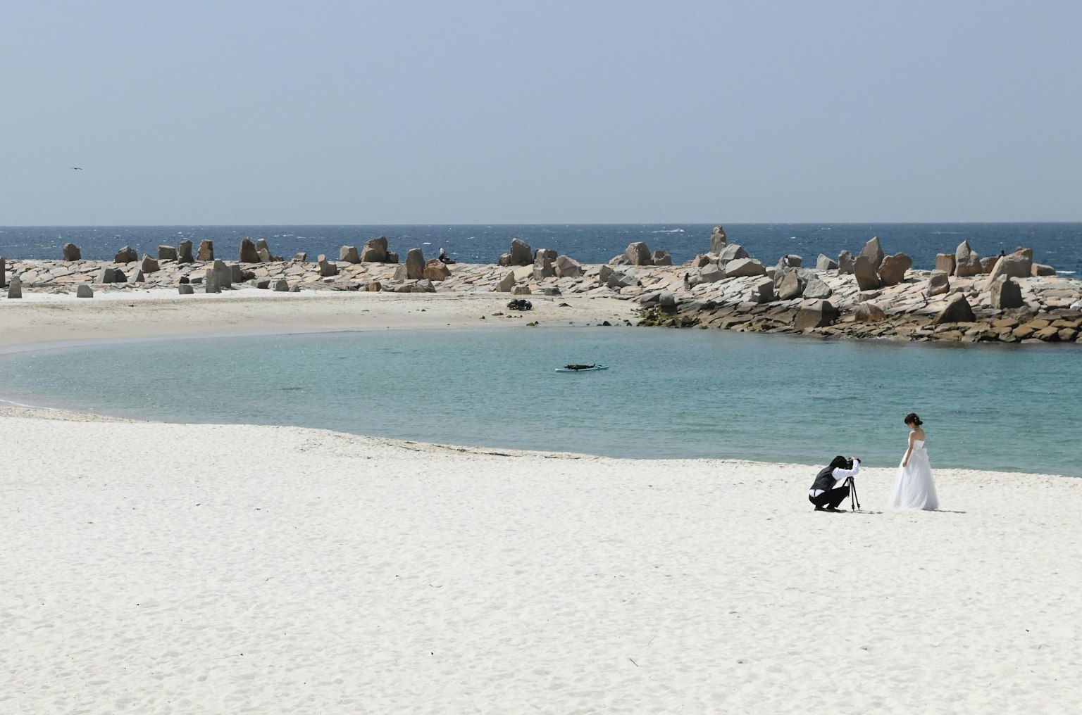 Sepasang kekasih mengambil foto pernikahan di pantai berpasir putih dekat laut