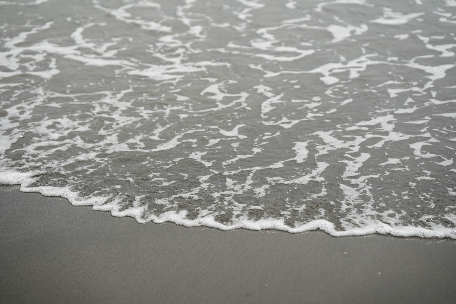 Immagine di onde che si infrangono su una spiaggia sabbiosa