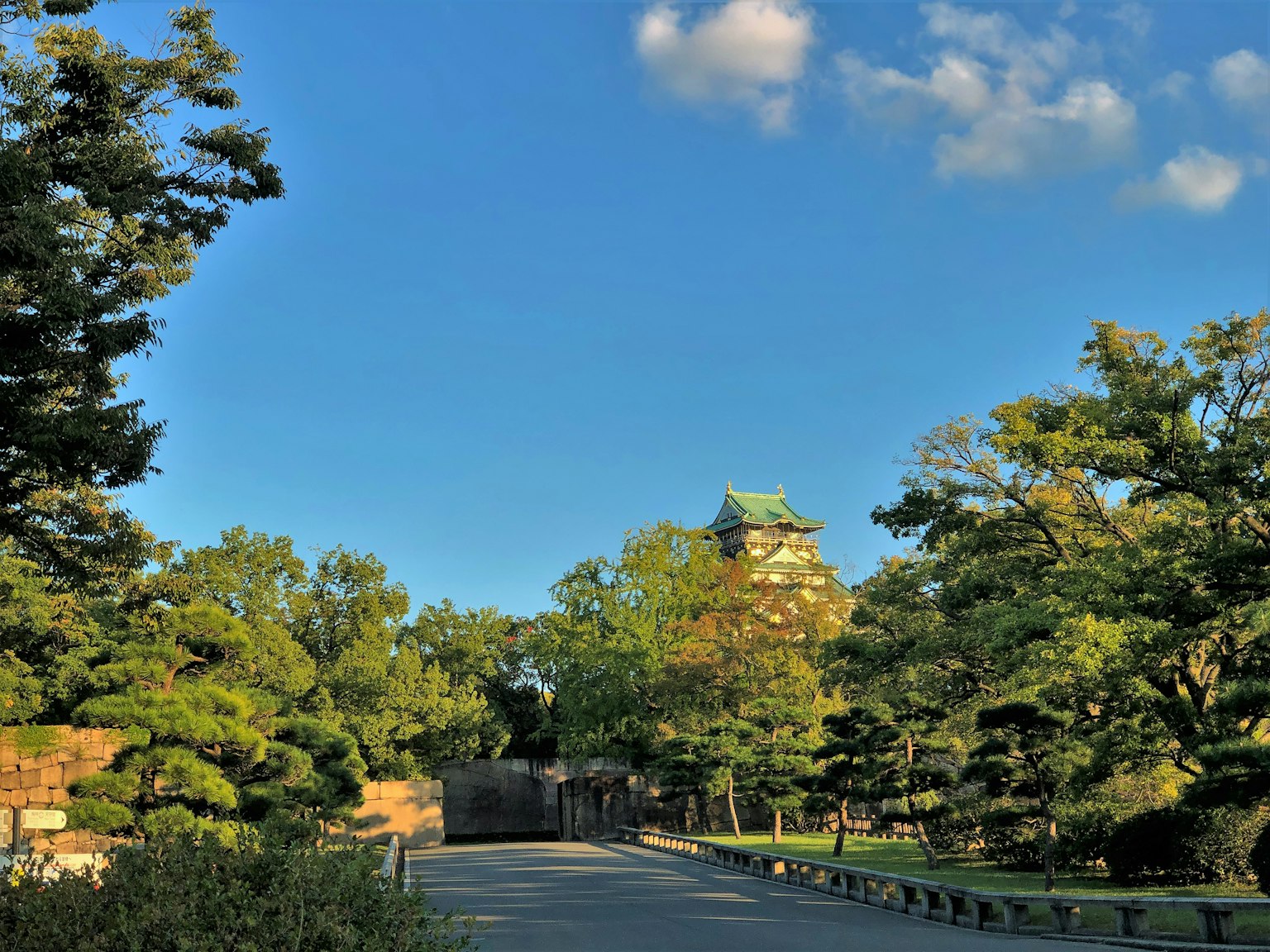 Vista escénica de un parque verde y un castillo bajo un cielo azul claro