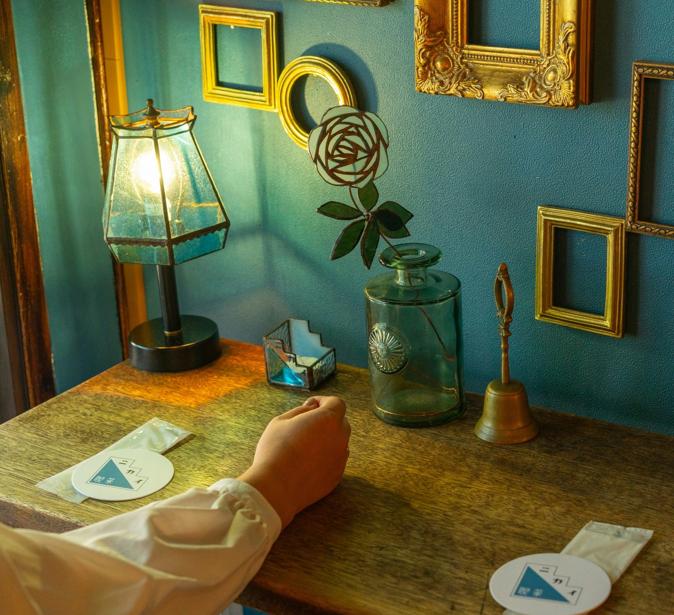 A quiet tabletop scene with a lamp and small objects against a blue wall