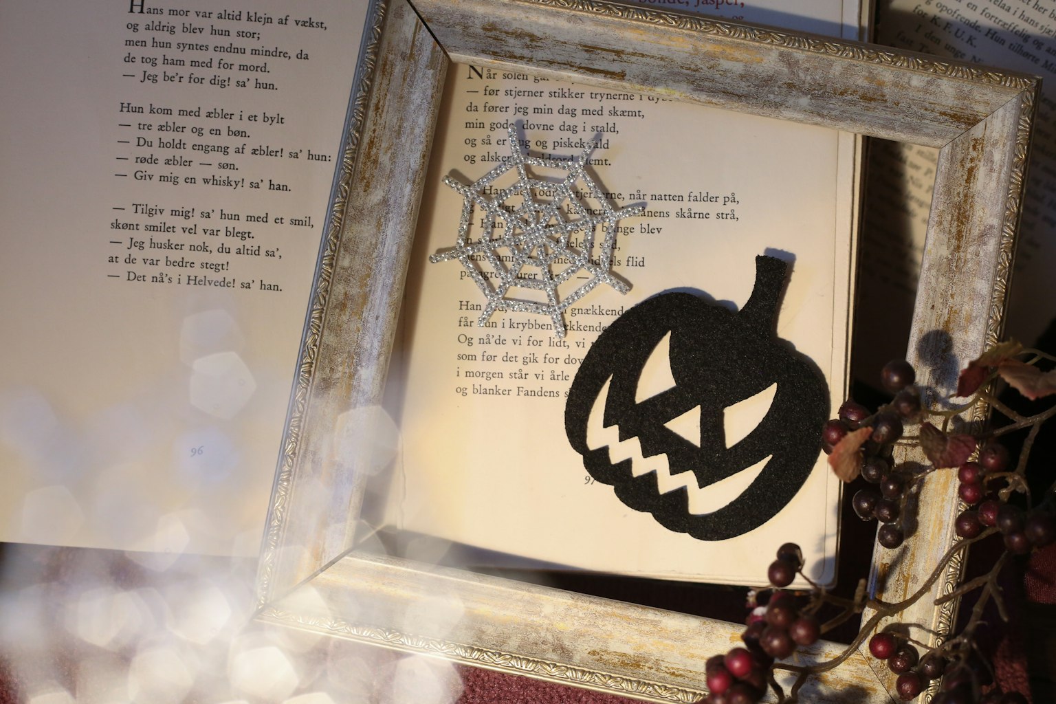 Sebuah bingkai bertema Halloween dengan labu dan jaring laba-laba di halaman buku