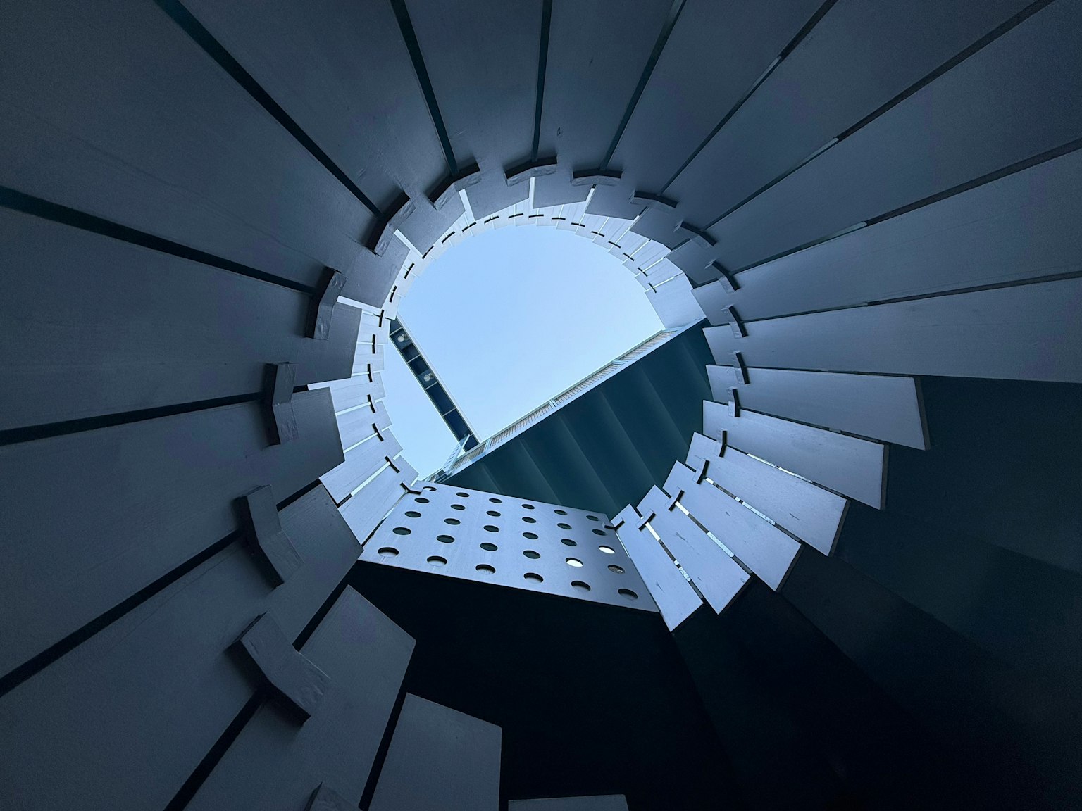 Vue vers le haut à travers une structure architecturale circulaire révélant le ciel bleu