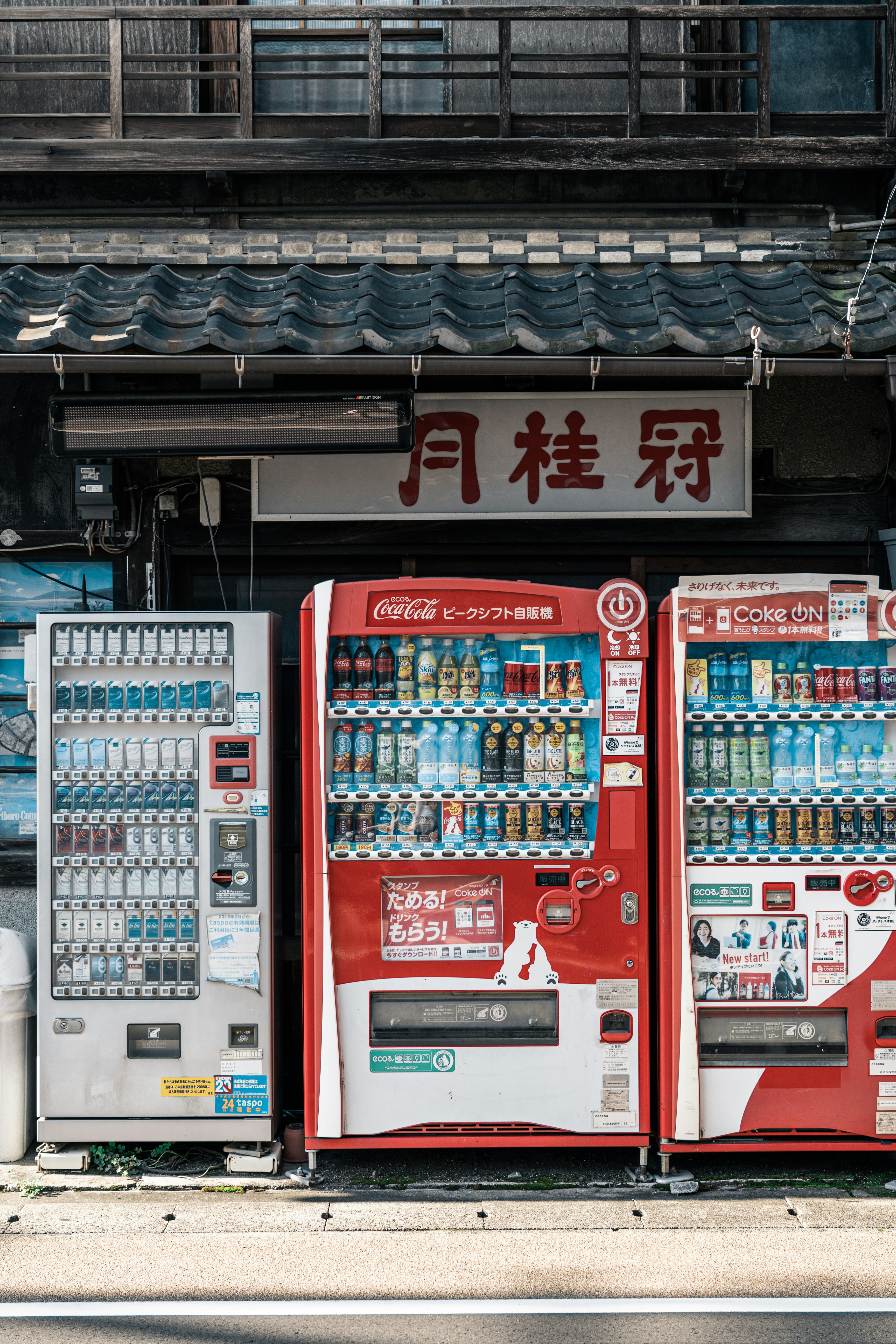 軒先に並ぶ自動販売機と看板のある商店街の路地