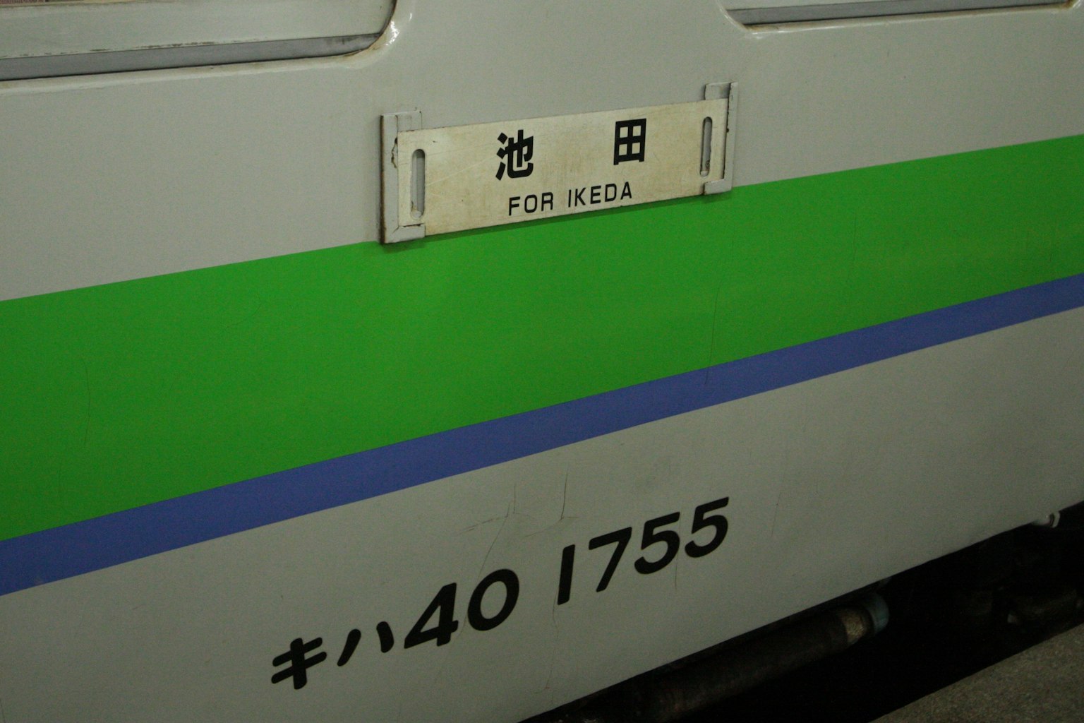 Vista laterale di un treno giapponese con destinazione Ikeda e numero del treno