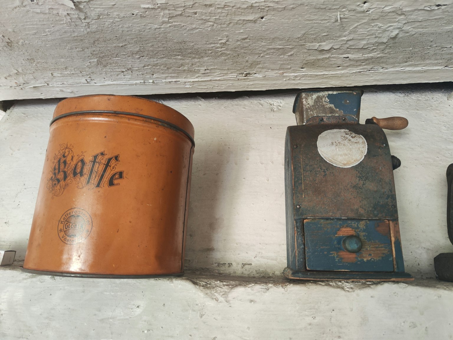 Une vieille boîte de café et un moulin à café exposés côte à côte