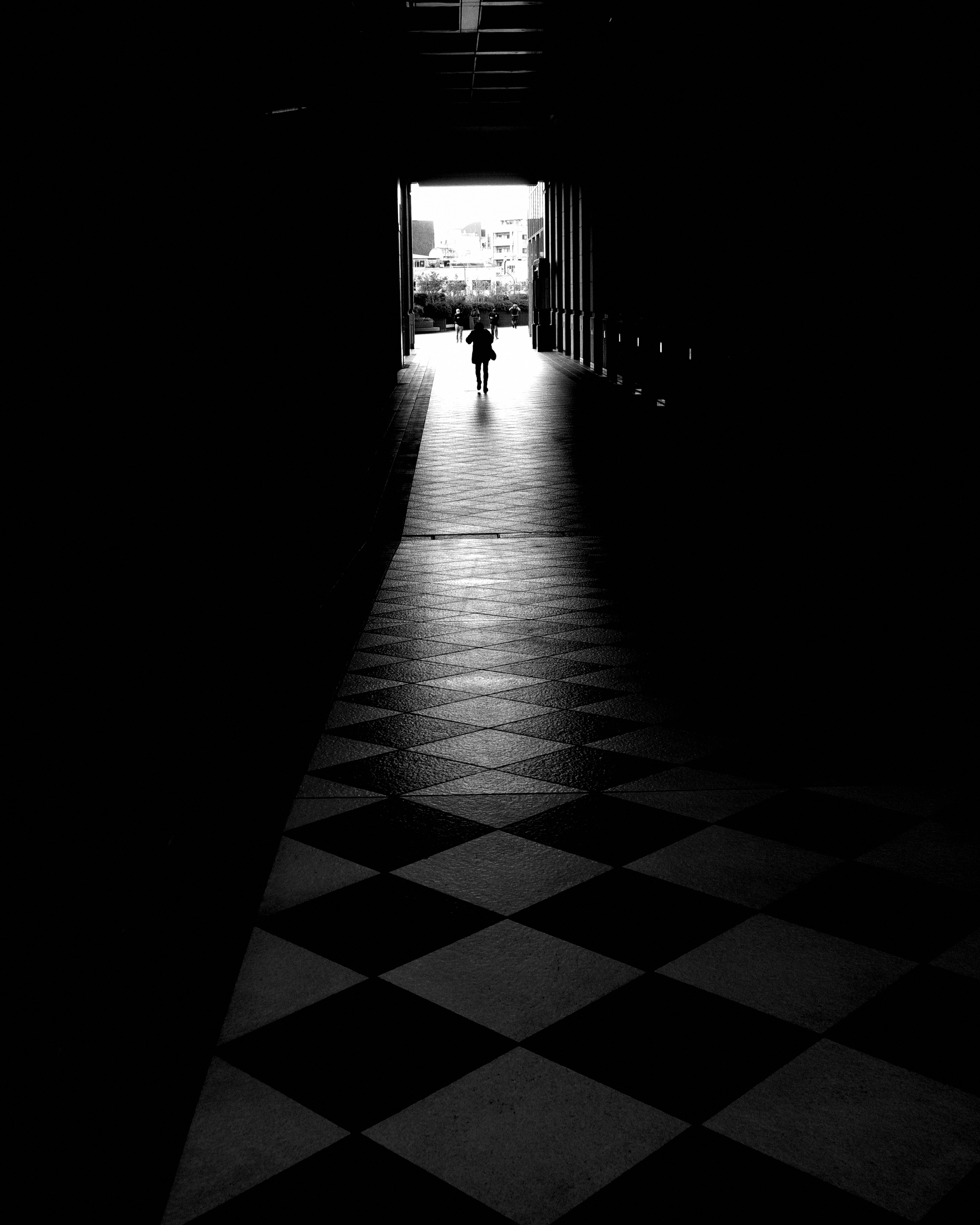 黒いアーチの奥に続く石畳の通路と人影