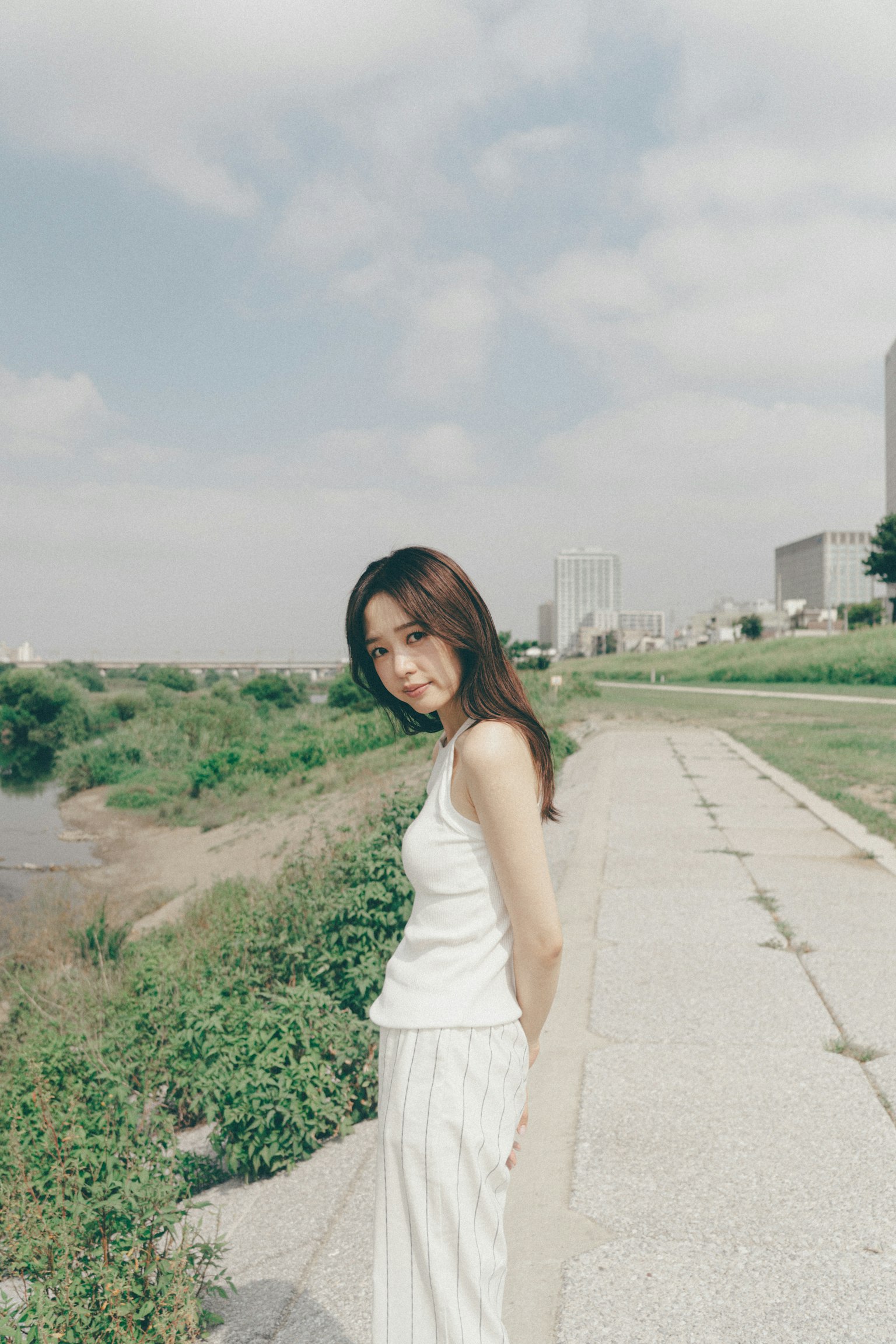 흰색 옷을 입은 여성이 강가의 길을 걷고 있다