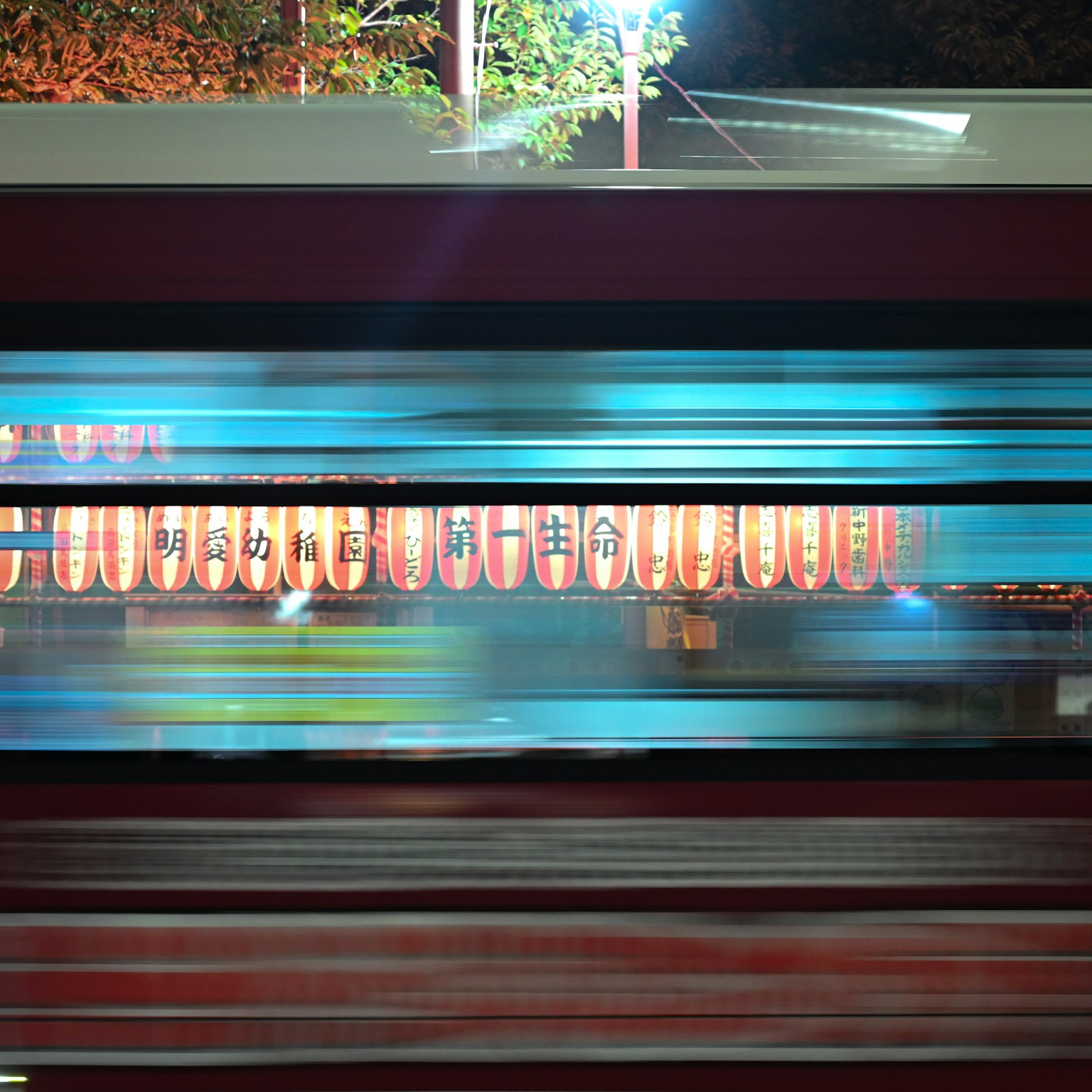 夜の街を走る電車と提灯の光が流れる様子