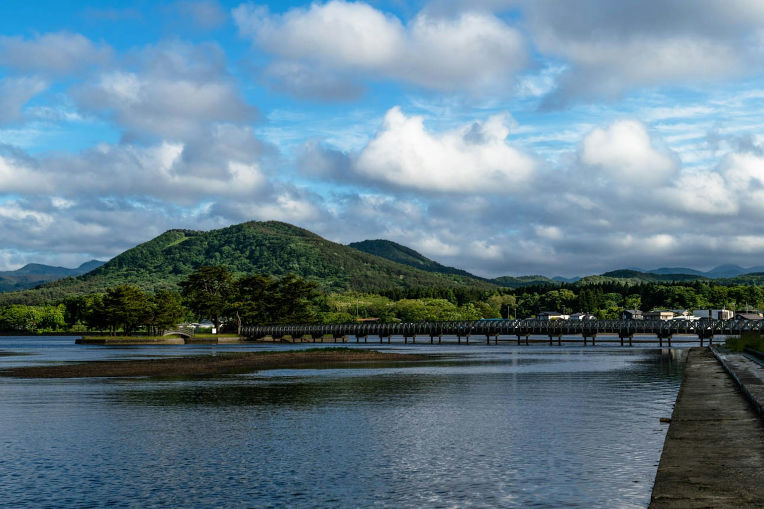 風景如畫的藍天白雲 綠色山丘和寧靜水面 可見的橋和小鎮