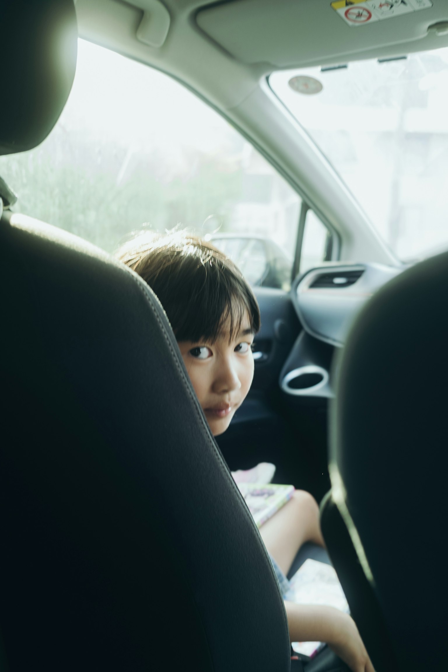 車の後部座席に座っている子供の顔が見える