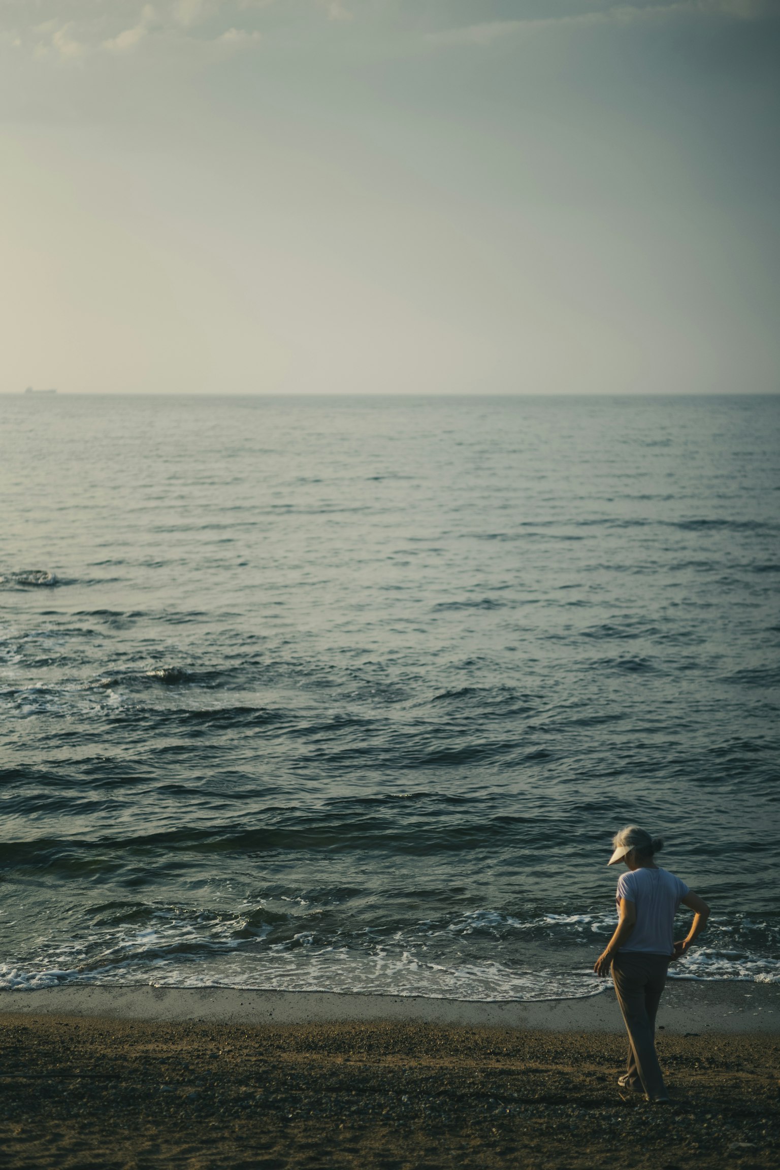 A person gazing at the calm sea on a beach