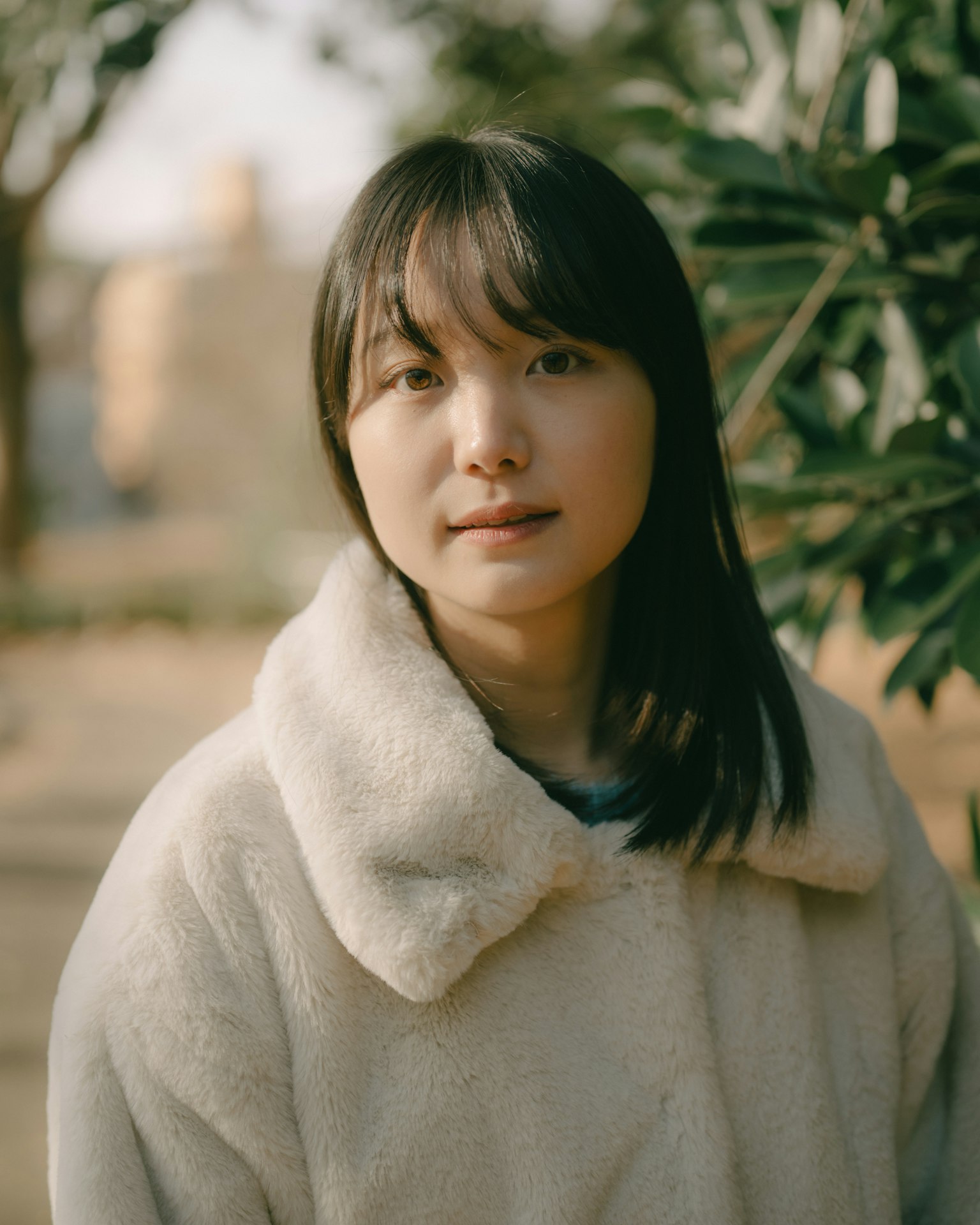나뭇잎 사이에 서 있는 여성의 초상화, 흰색 코트를 입고 있음