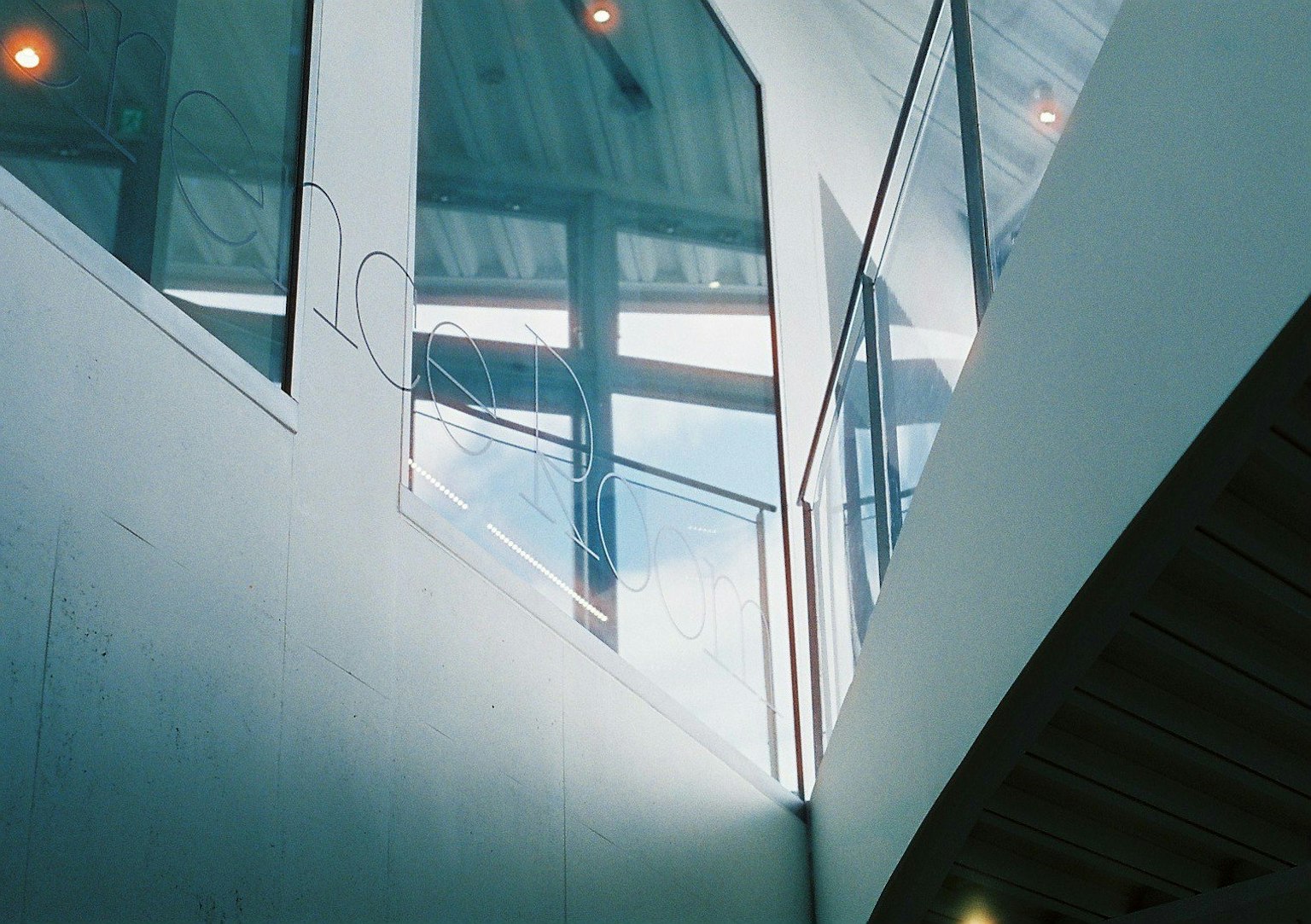 Interno moderno di un edificio con parapetto in vetro e luce naturale che entra dal soffitto
