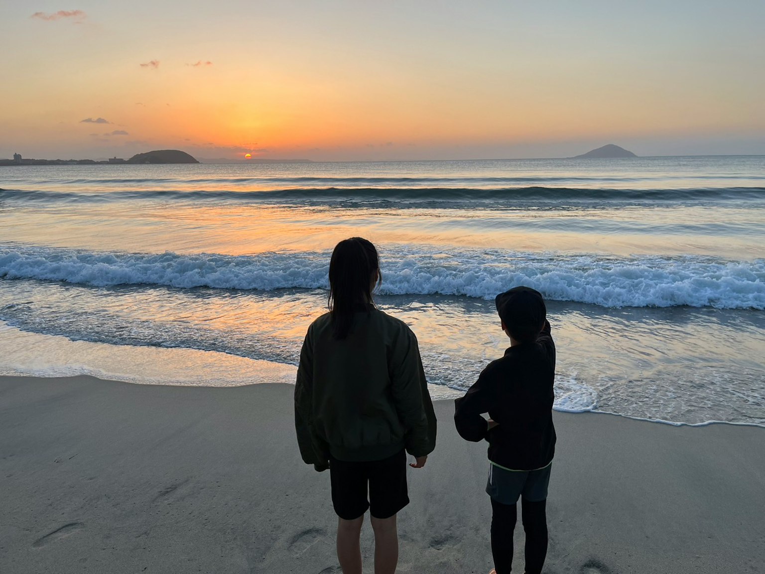 Deux enfants regardant le coucher de soleil sur la plage