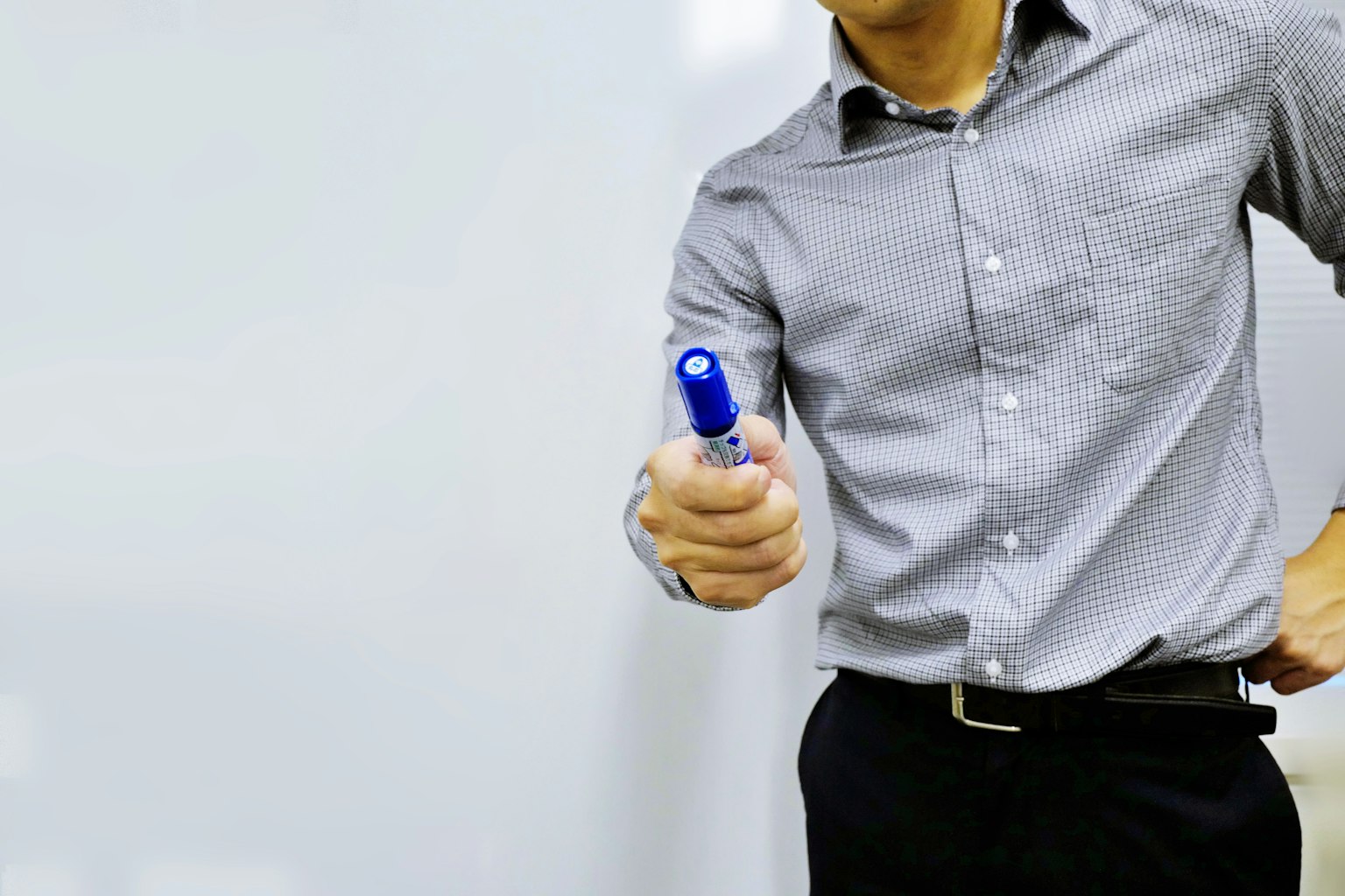 Hombre sosteniendo un marcador azul en un entorno de negocios