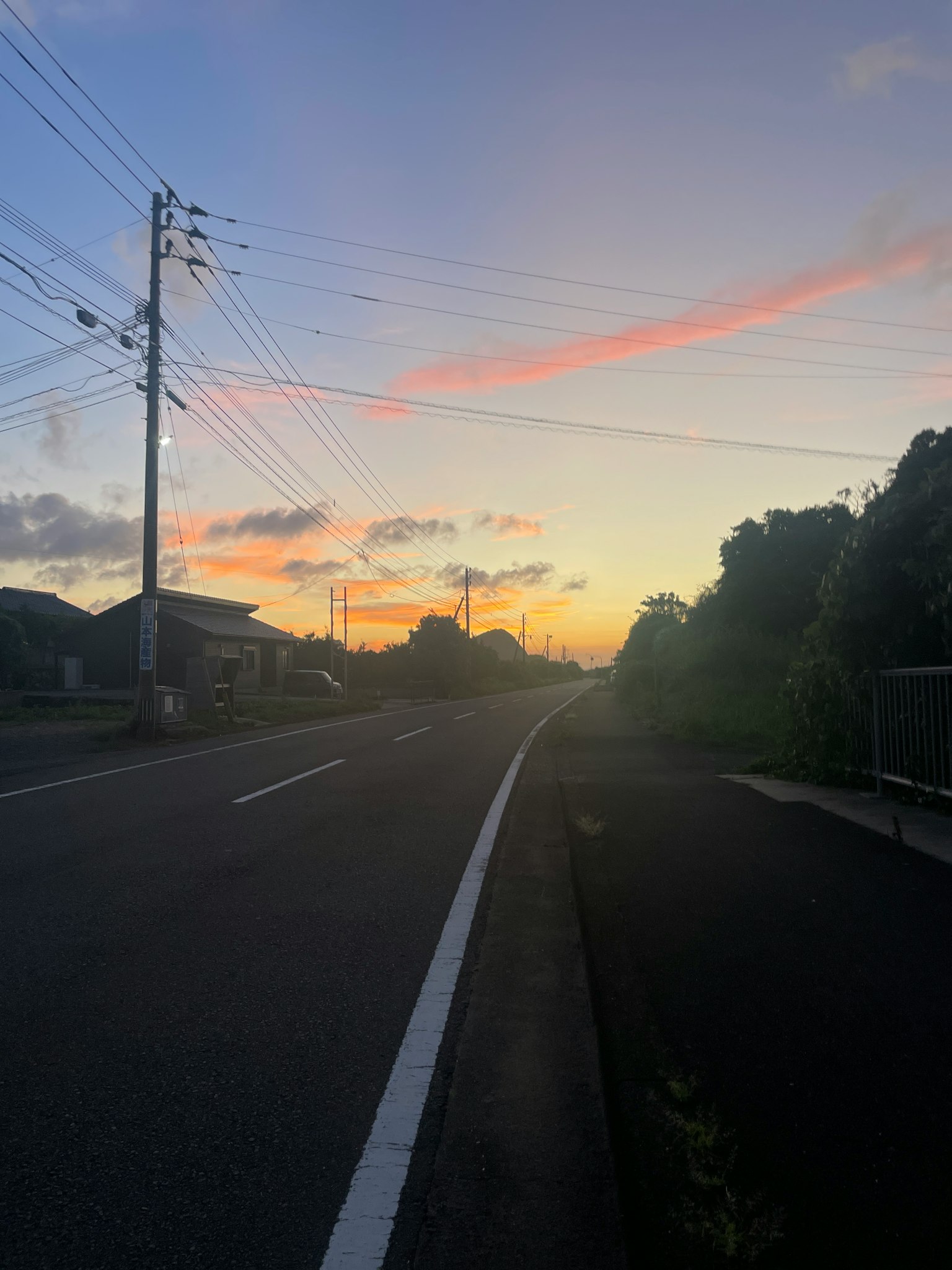 夕焼けの空と道路の風景 電柱と住宅が見える