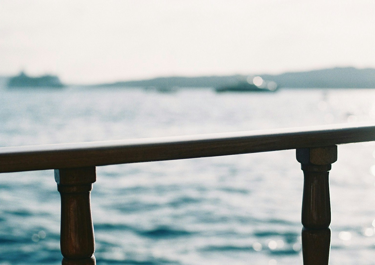 Close-up of a wooden railing against a backdrop of the ocean