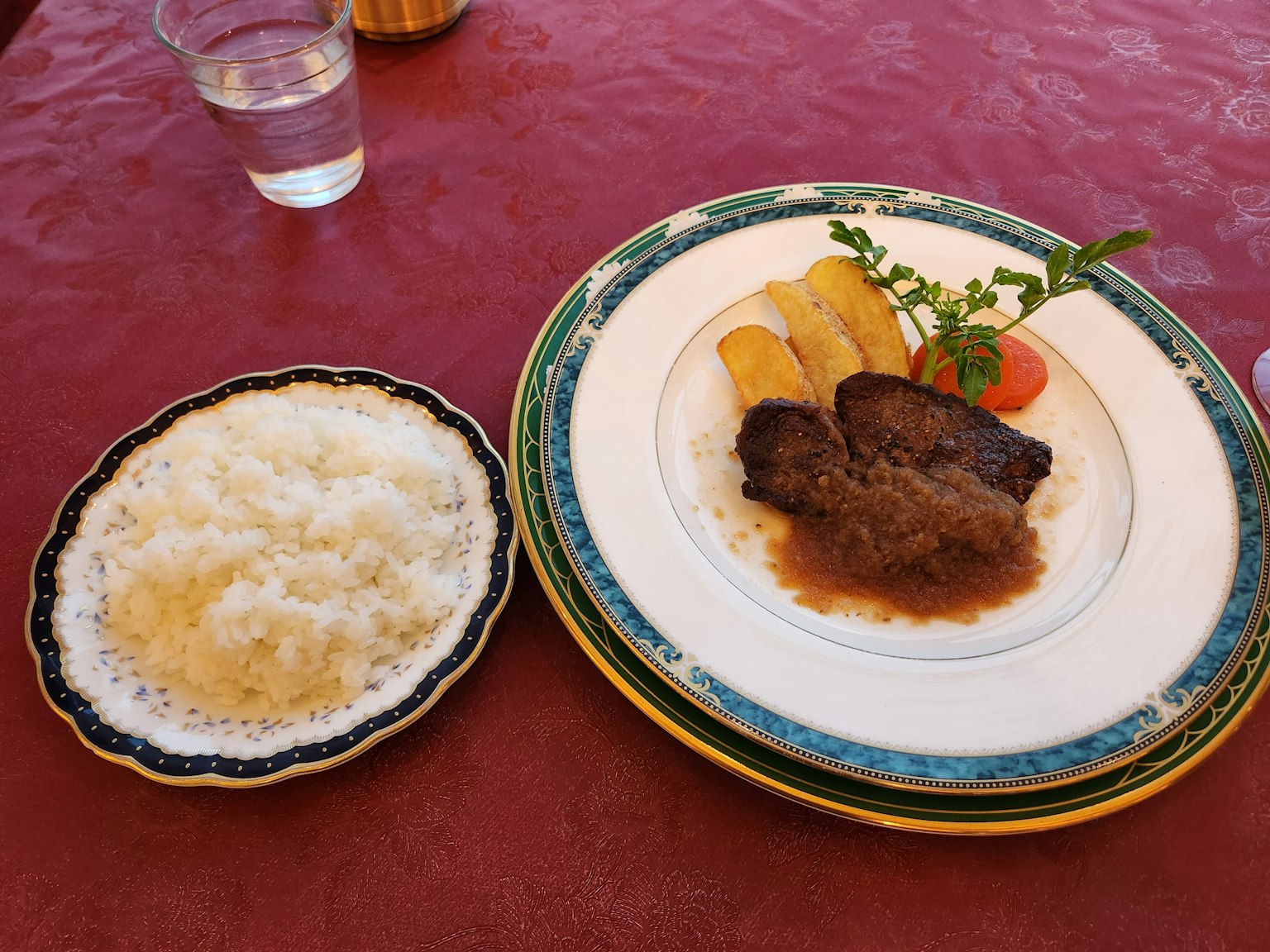 Un piatto con carne accompagnato da banane e una piccola ciotola di riso