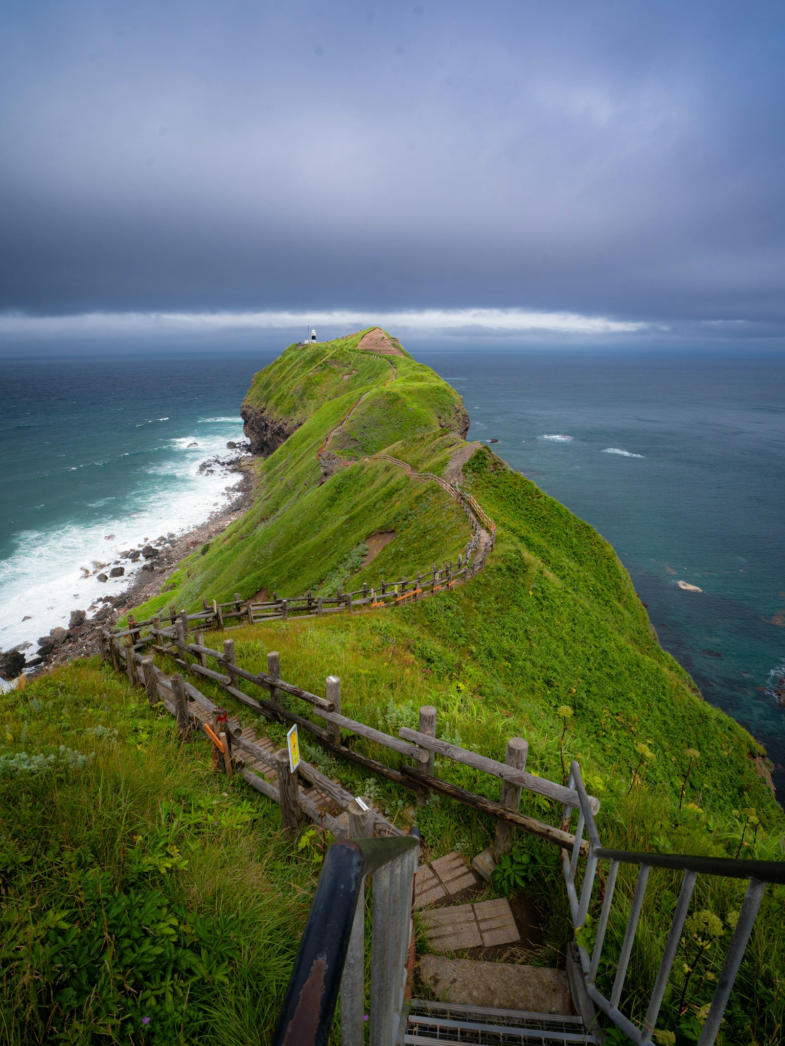Stairway leading down a green hill to the ocean