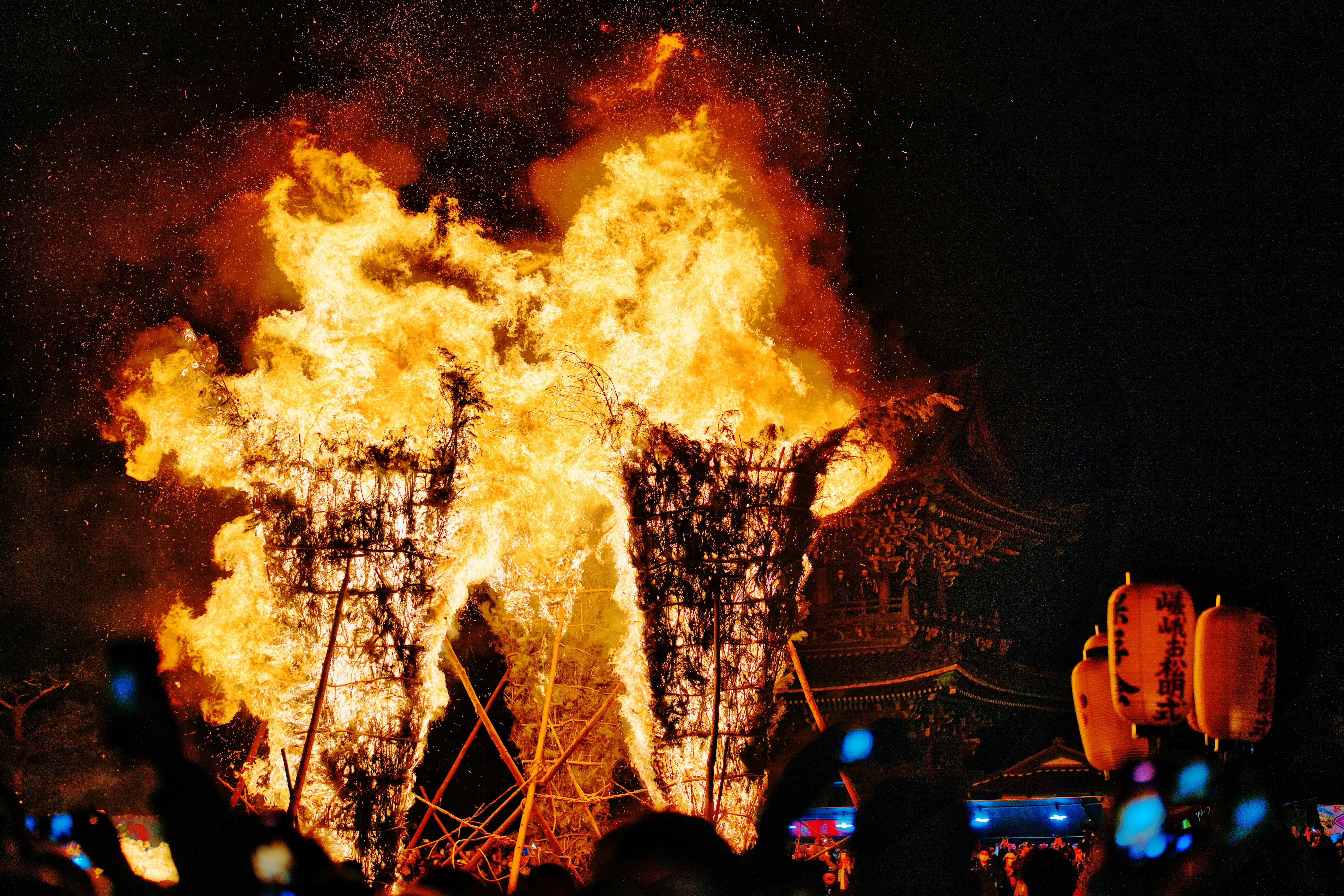 夜の祭りで燃え上がる大きな炎と観客のシルエット