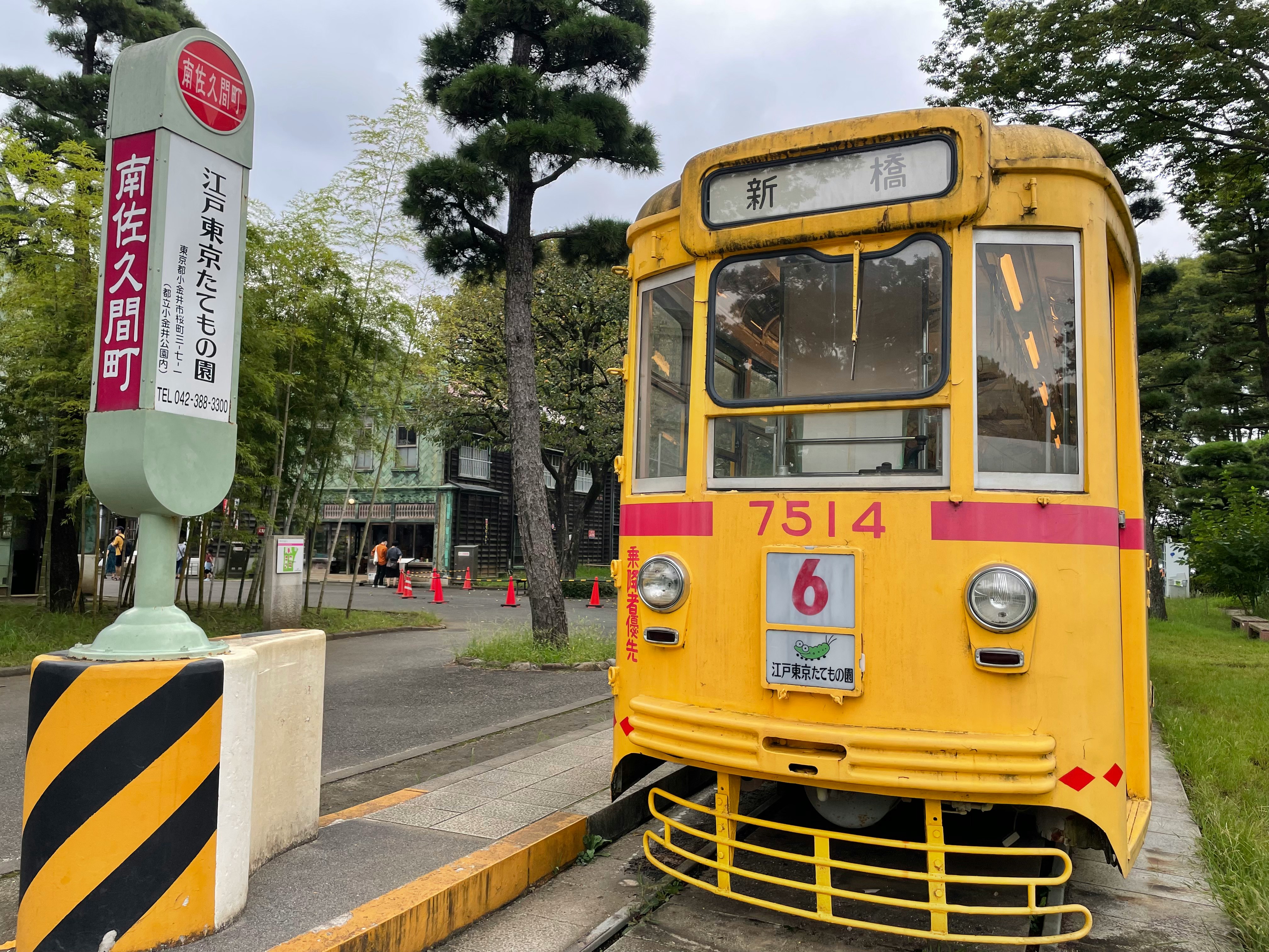 黄色い路面電車と標識のある駅前の通路