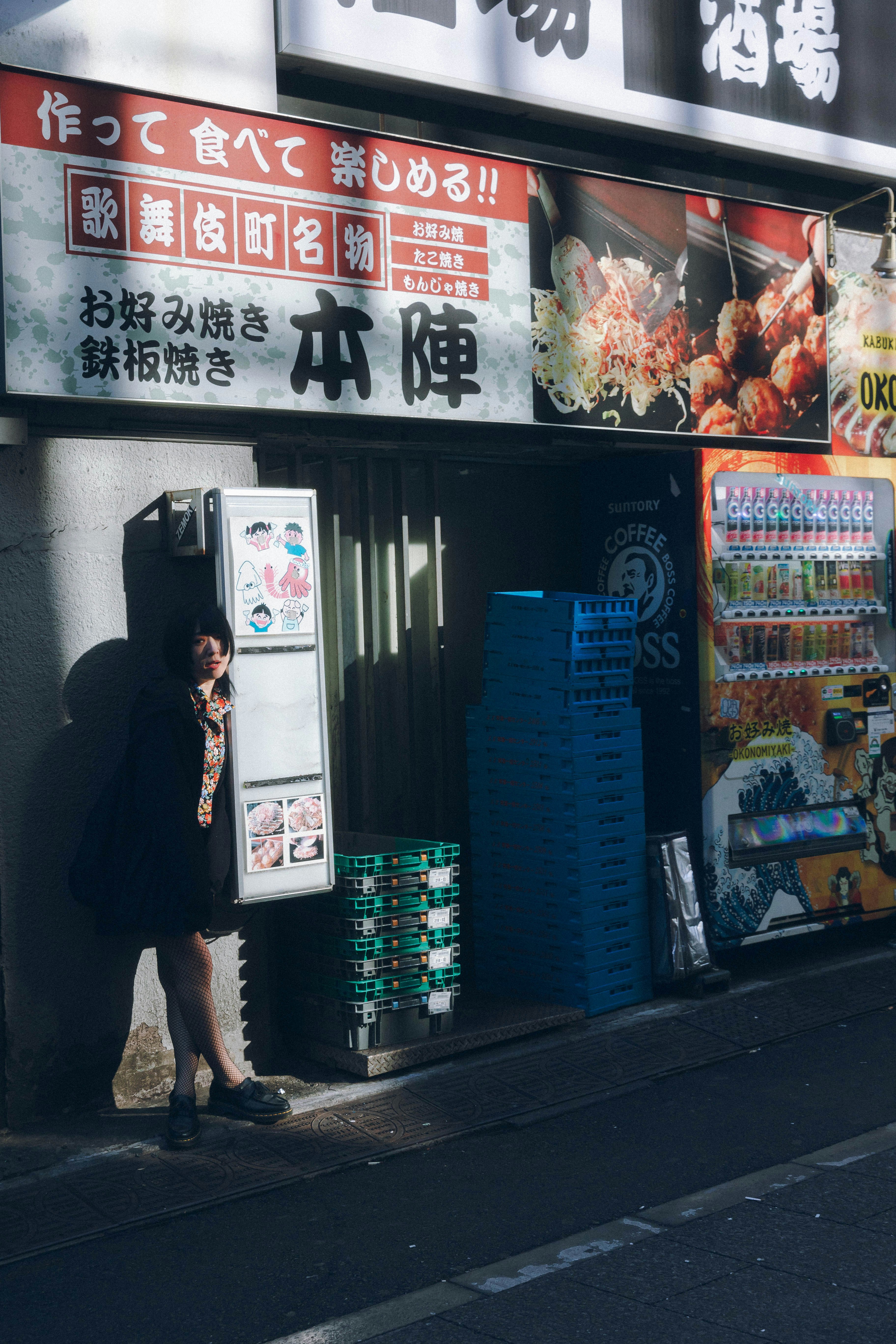 路地の店先に並ぶ看板と自販機のある飲食店