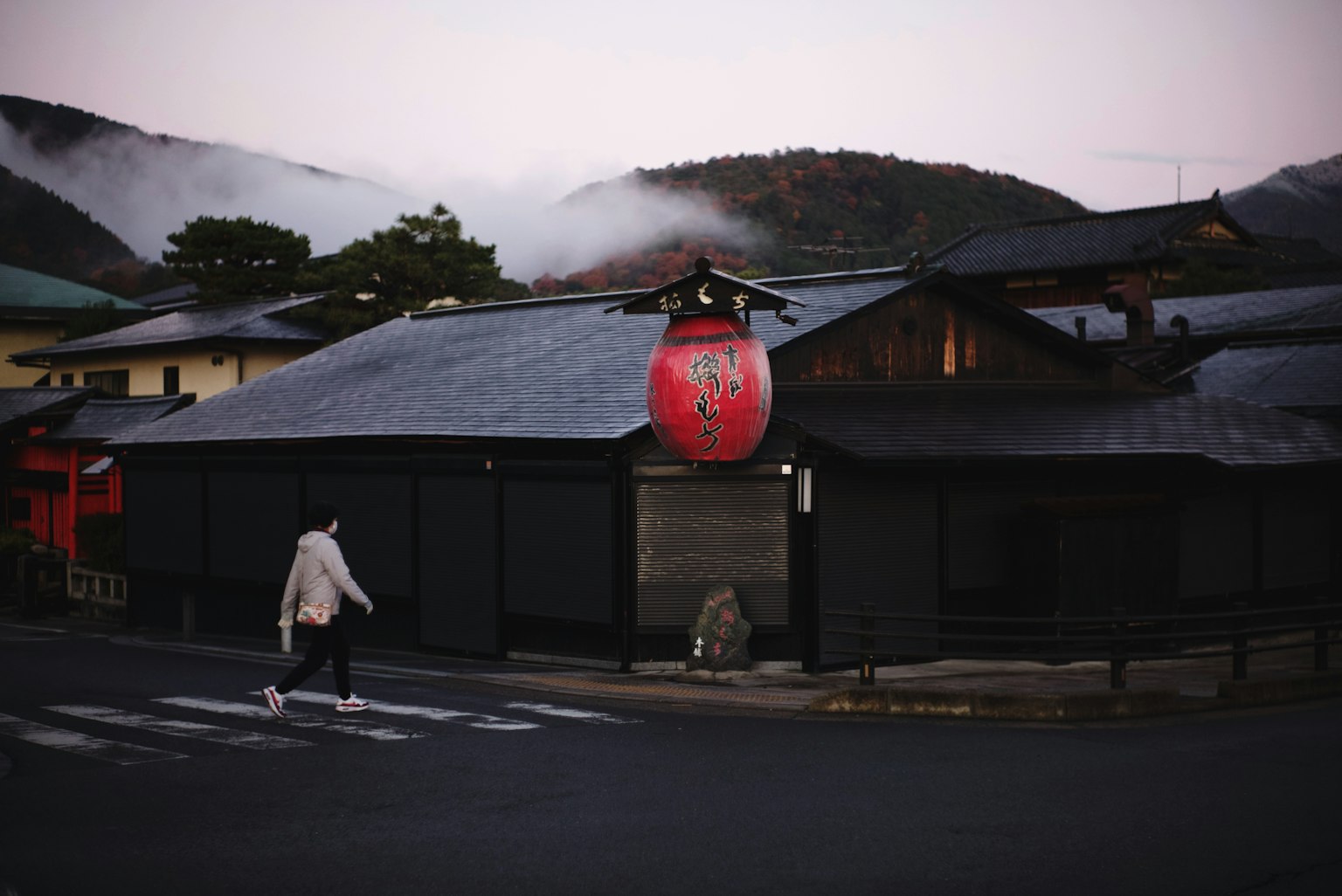 Bâtiment traditionnel japonais noir avec une lanterne rouge au crépuscule