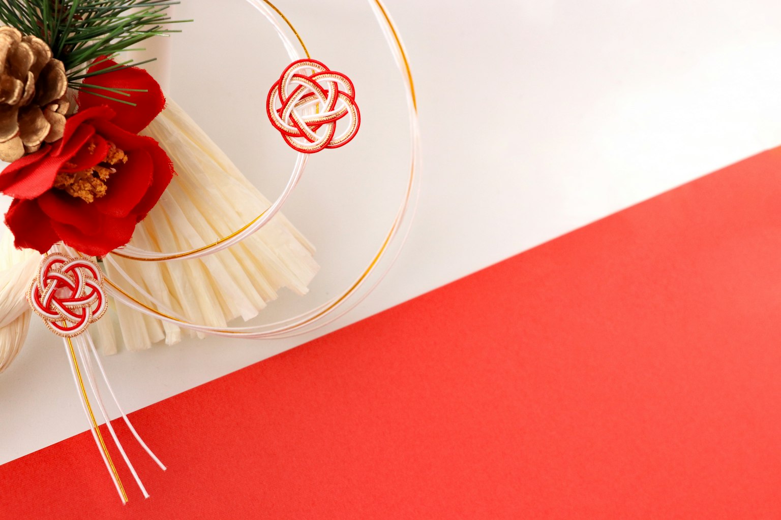 Japanese New Year decoration featuring pine cones and red flowers on a red and white background
