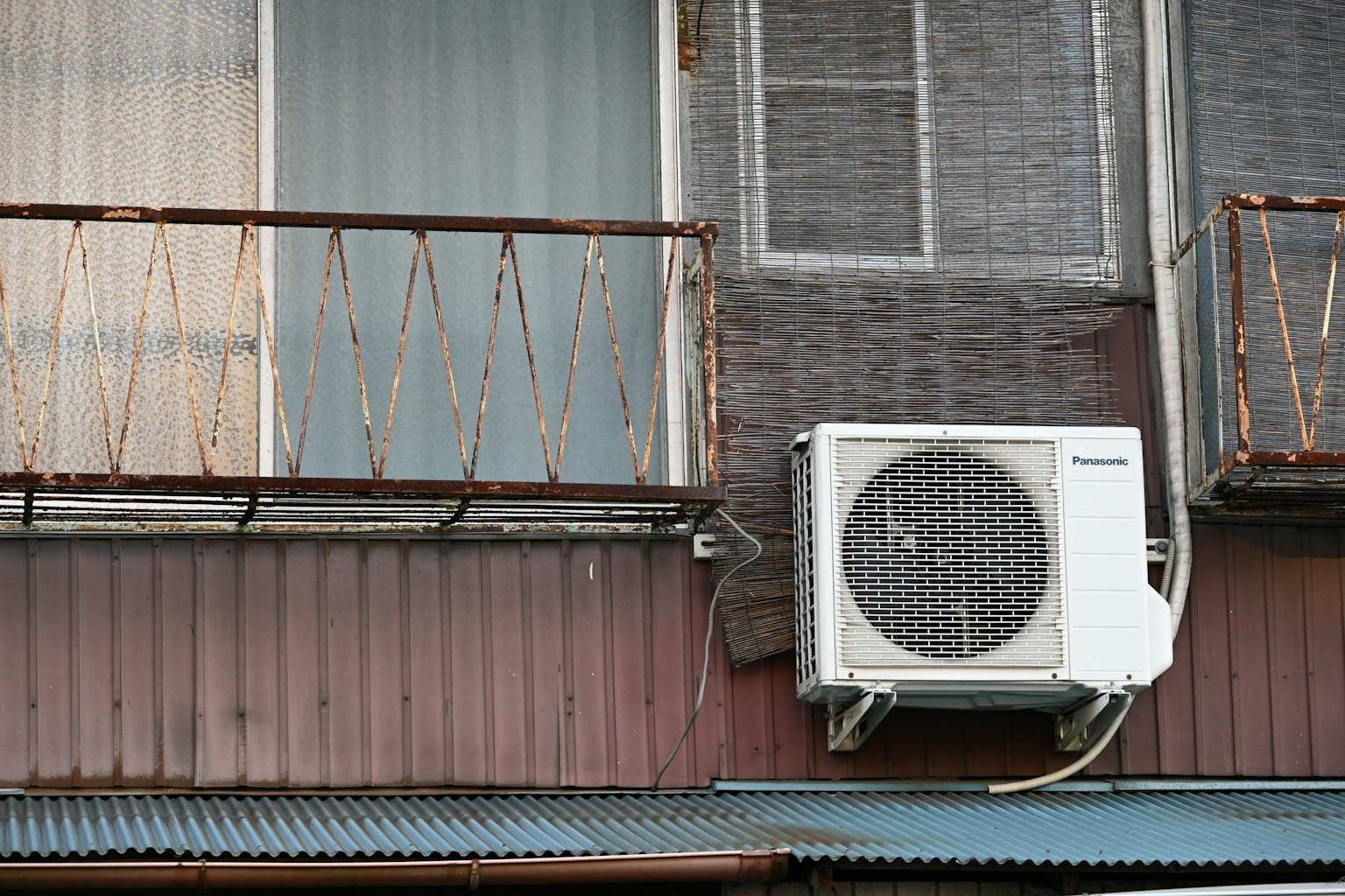 오래된 건물 벽에 설치된 에어컨과 녹슨 발코니 난간