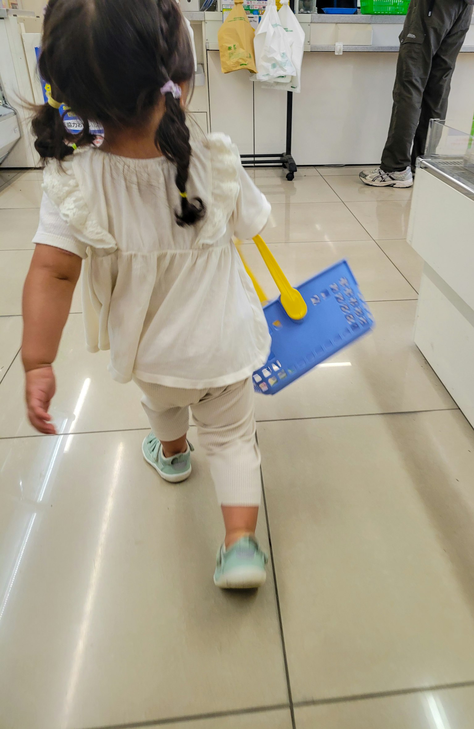 穿着白色衣服的小女孩手持蓝色铲子走路